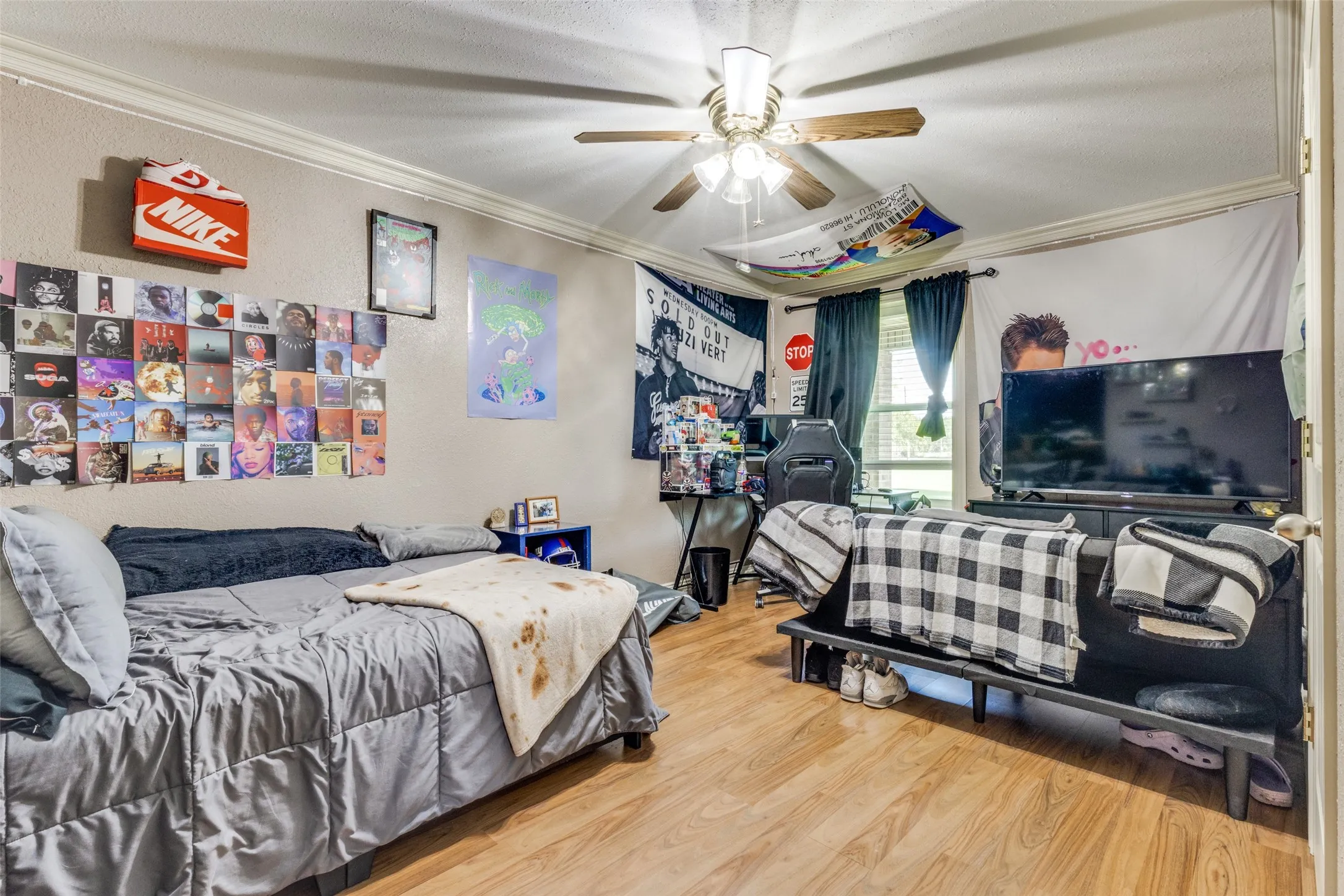 Bedroom with ornamental molding, wood finished floors, a textured wall, and a ceiling fan