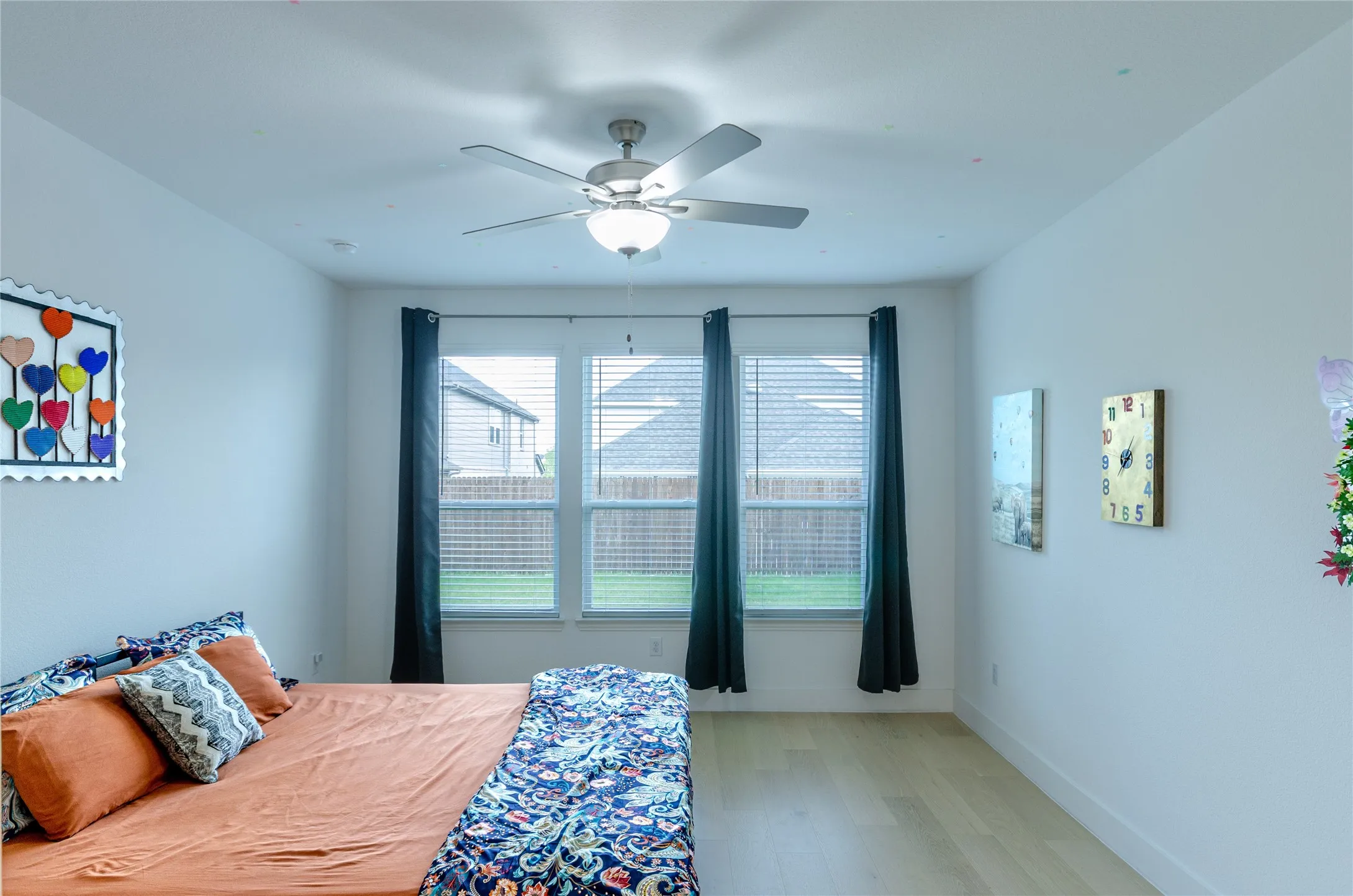 Bright interior space featuring light wood-finish flooring, a ceiling fan with integrated lighting, and white walls