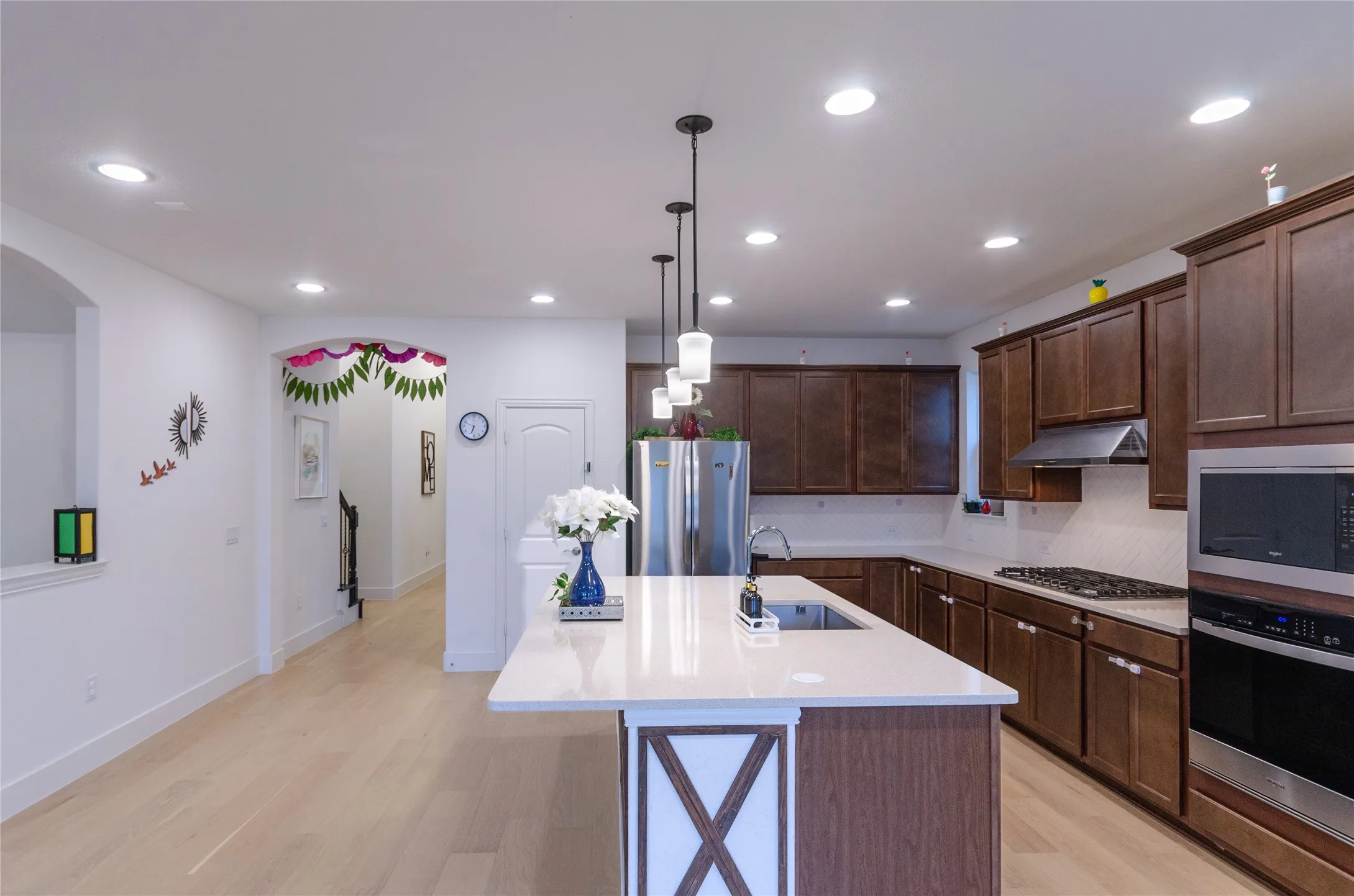 Gourmet kitchen with wood-finish cabinetry, stainless steel appliances, and a central island featuring a sink
