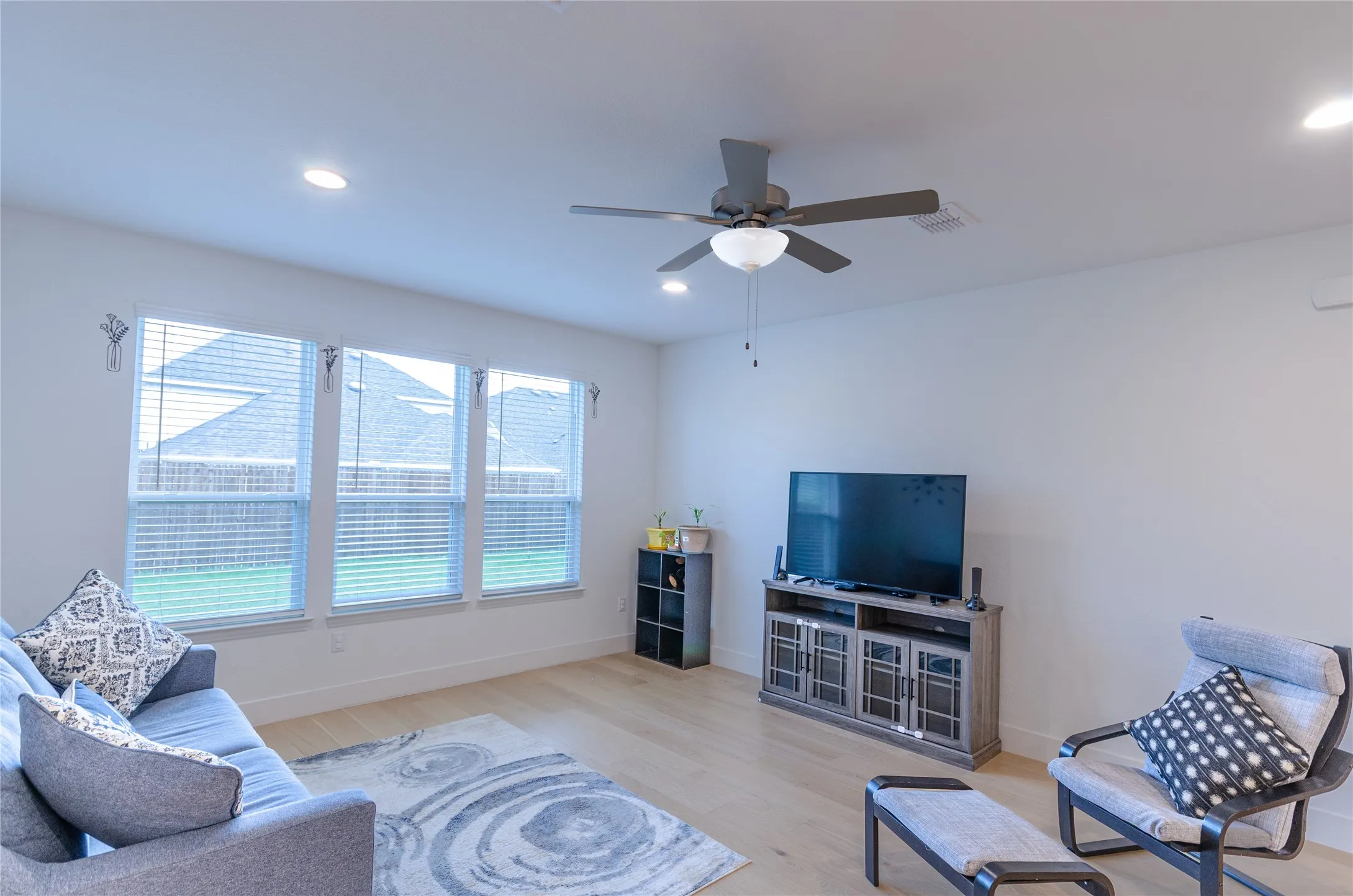 Open-concept living space featuring wood-finish flooring, recessed lighting, and a ceiling fan with light fixture