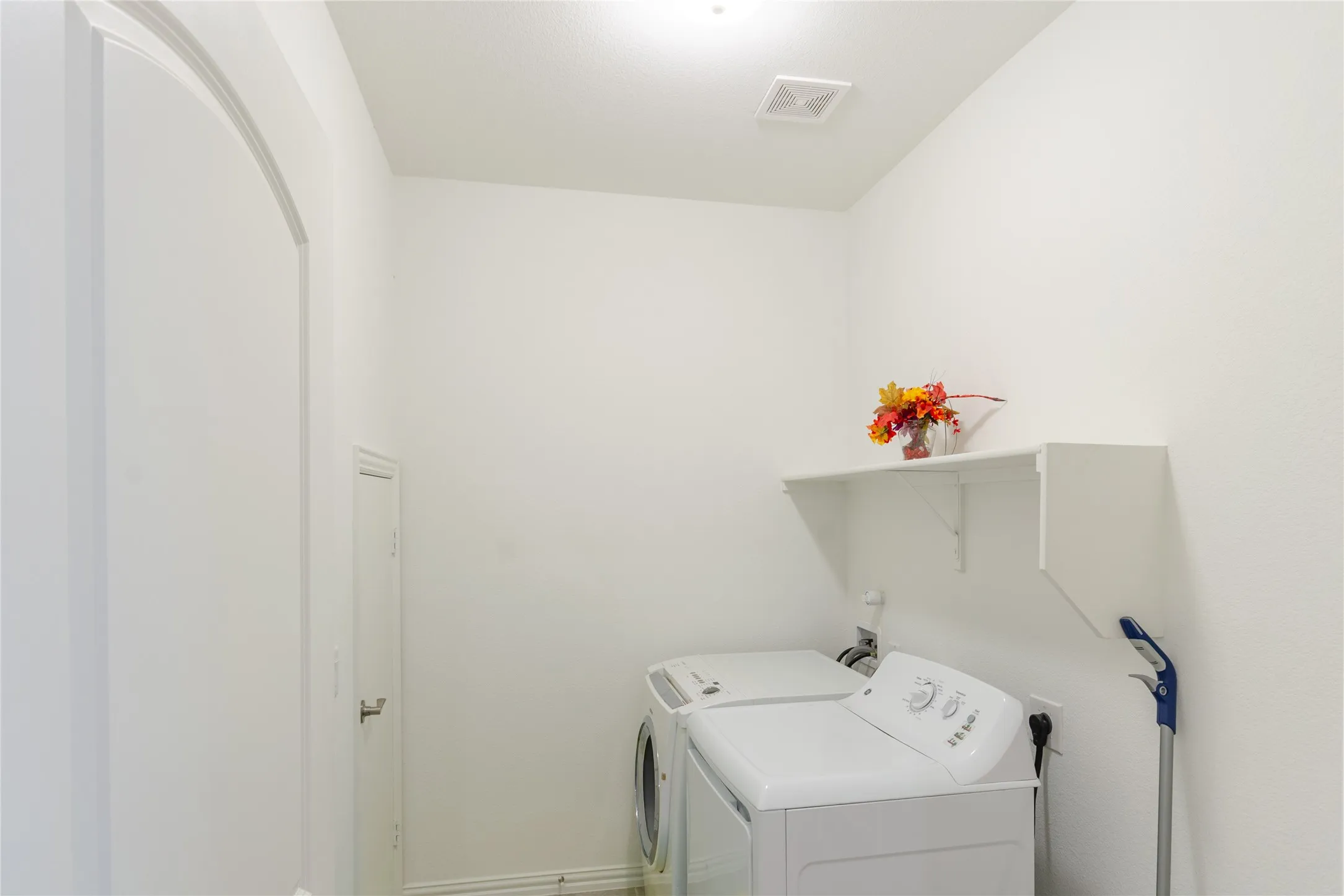 Dedicated utility space featuring a wall-mounted shelf, light fixture, and archway entry