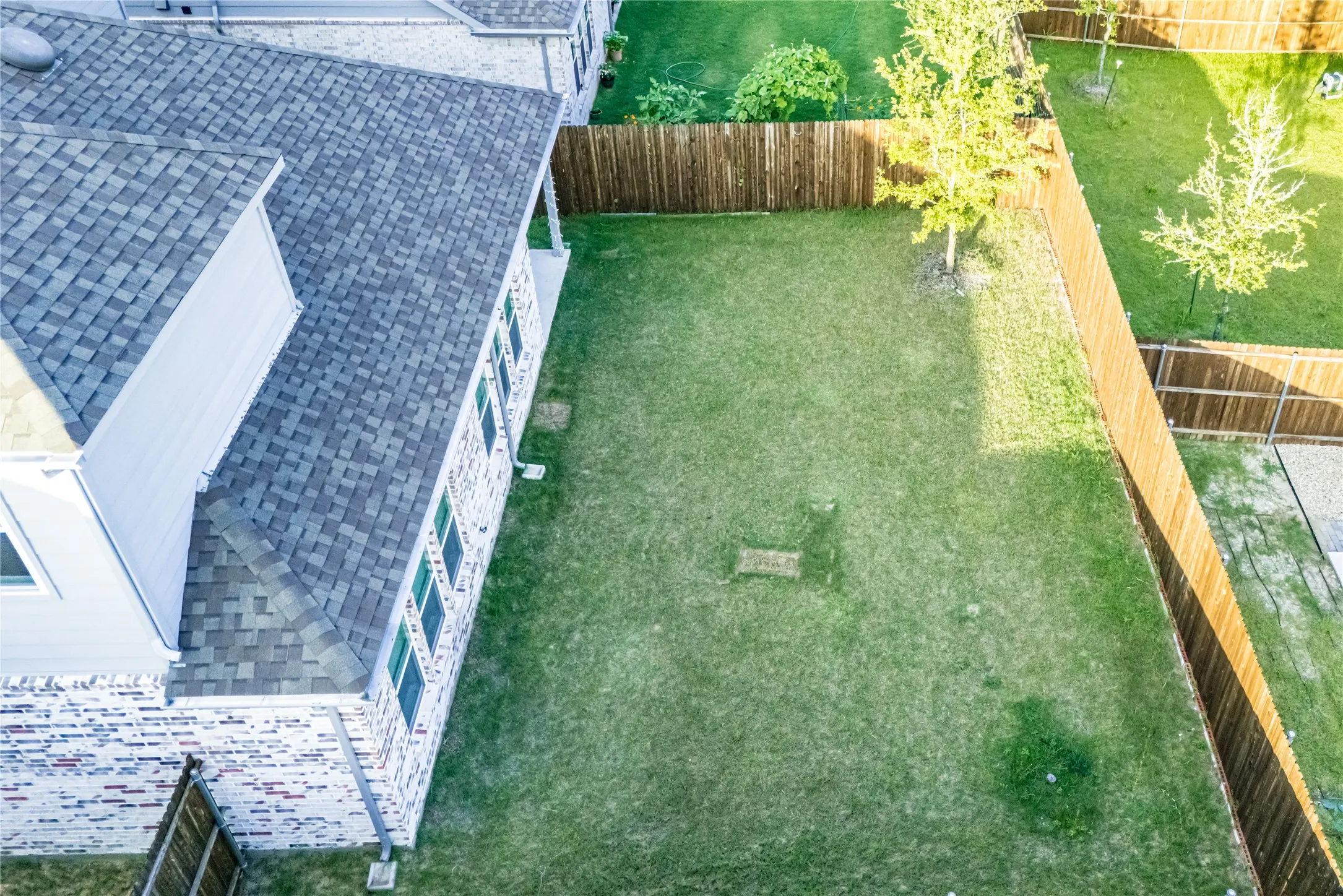 Expansive grassy backyard featuring a full perimeter wooden fence