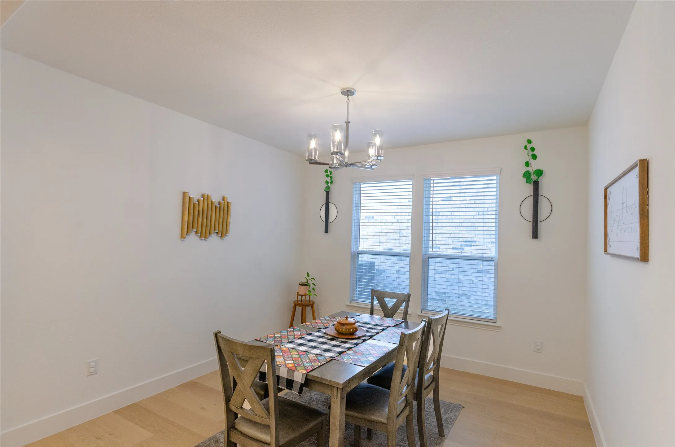 Dining area featuring light wood-finish flooring, white baseboards, and a modern chandelier