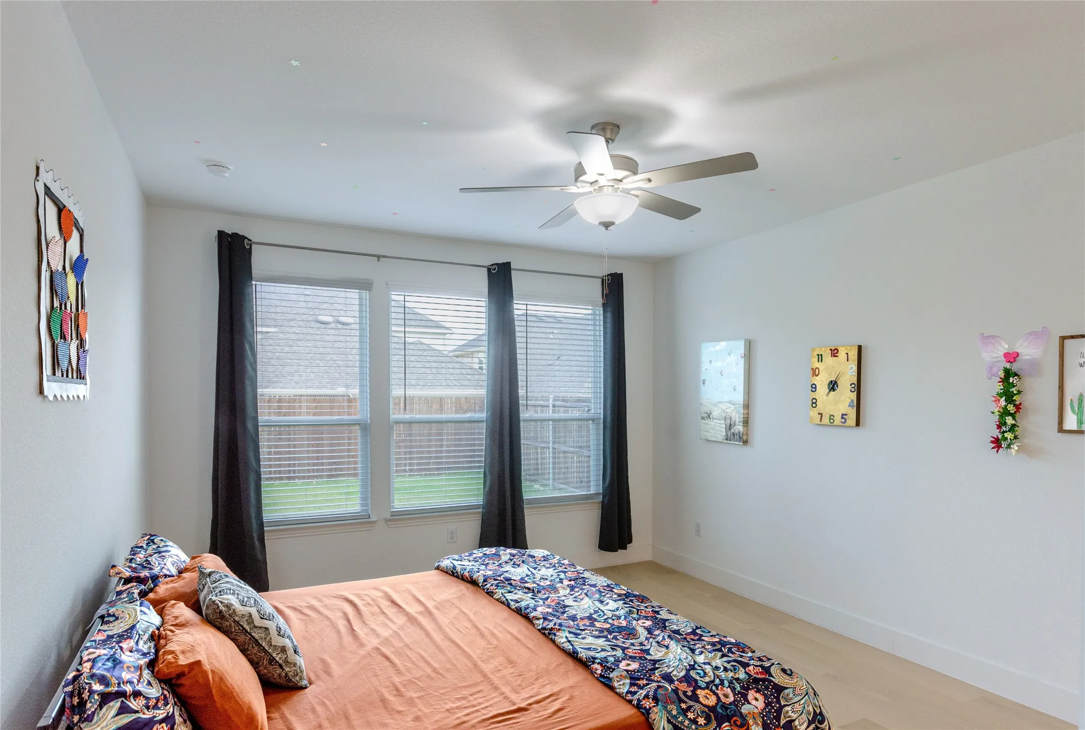 Bedroom featuring light wood-finish flooring, white walls, and a ceiling fan with integrated lighting