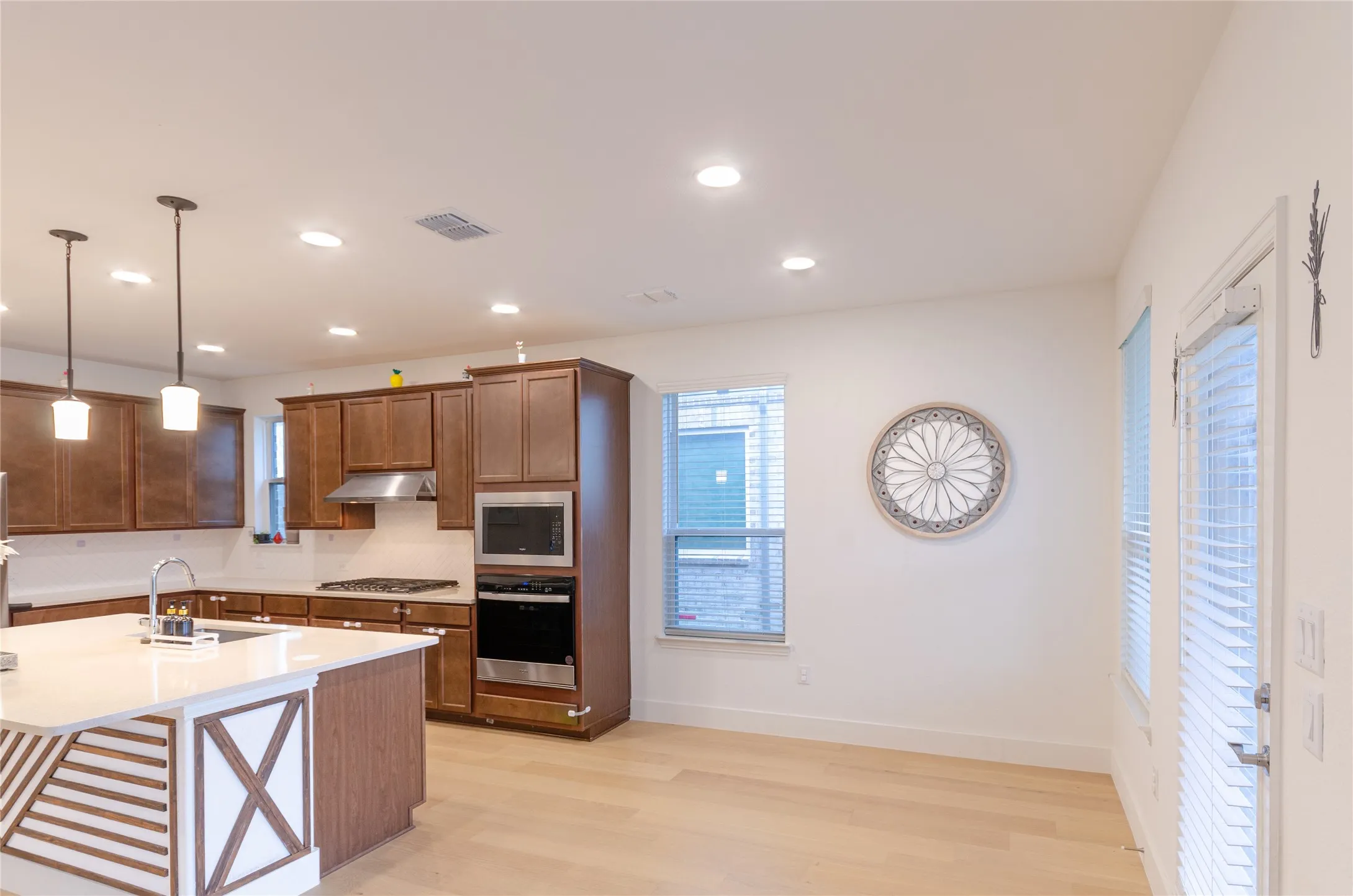 Breakfast area & Kitchen featuring recessed lighting, a central island with an integrated sink, dark wood cabinetry, and stainless steel appliances including a built-in microwave and oven
