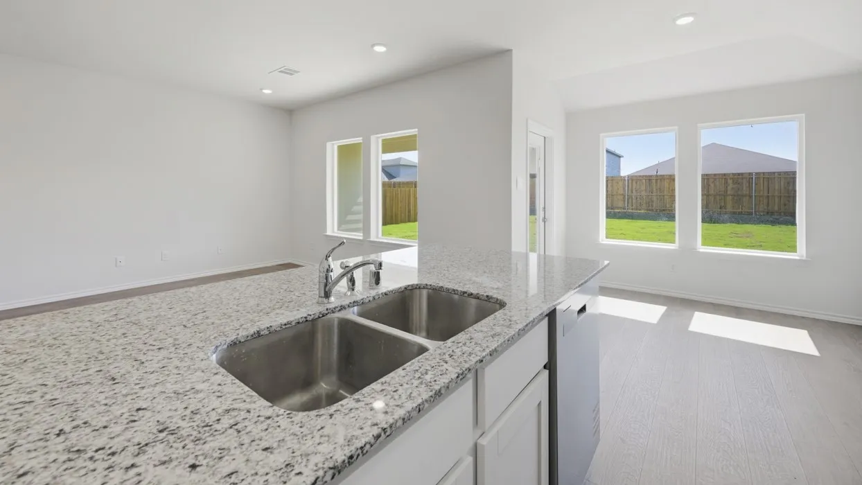 Kitchen island with a double stainless steel sink, chrome faucet, and speckled countertop