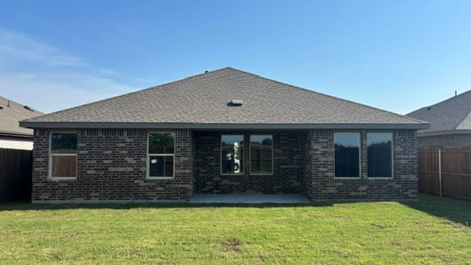 Brick exterior with a gabled roof and a concrete patio