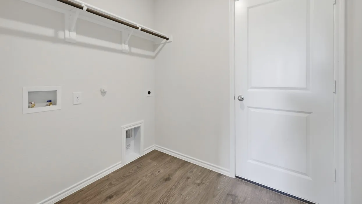 Utility room featuring wood-finish flooring, white baseboards, and a paneled door