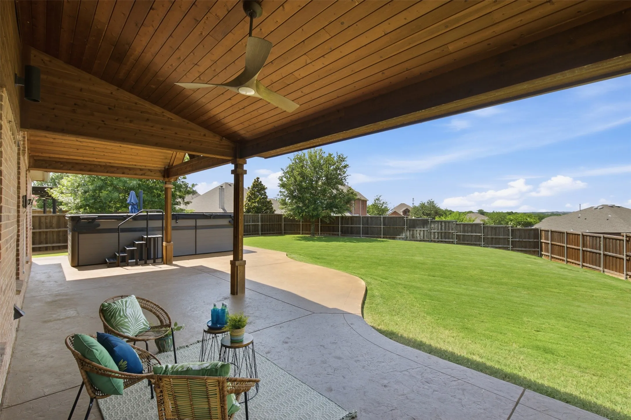Expansive concrete patio, covered outdoor living area, and dual-zone swim spa designed for entertaining.