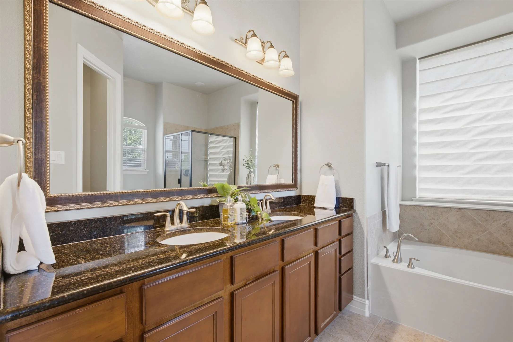 Primary bathroom with dual vanities, garden tub, and separate shower