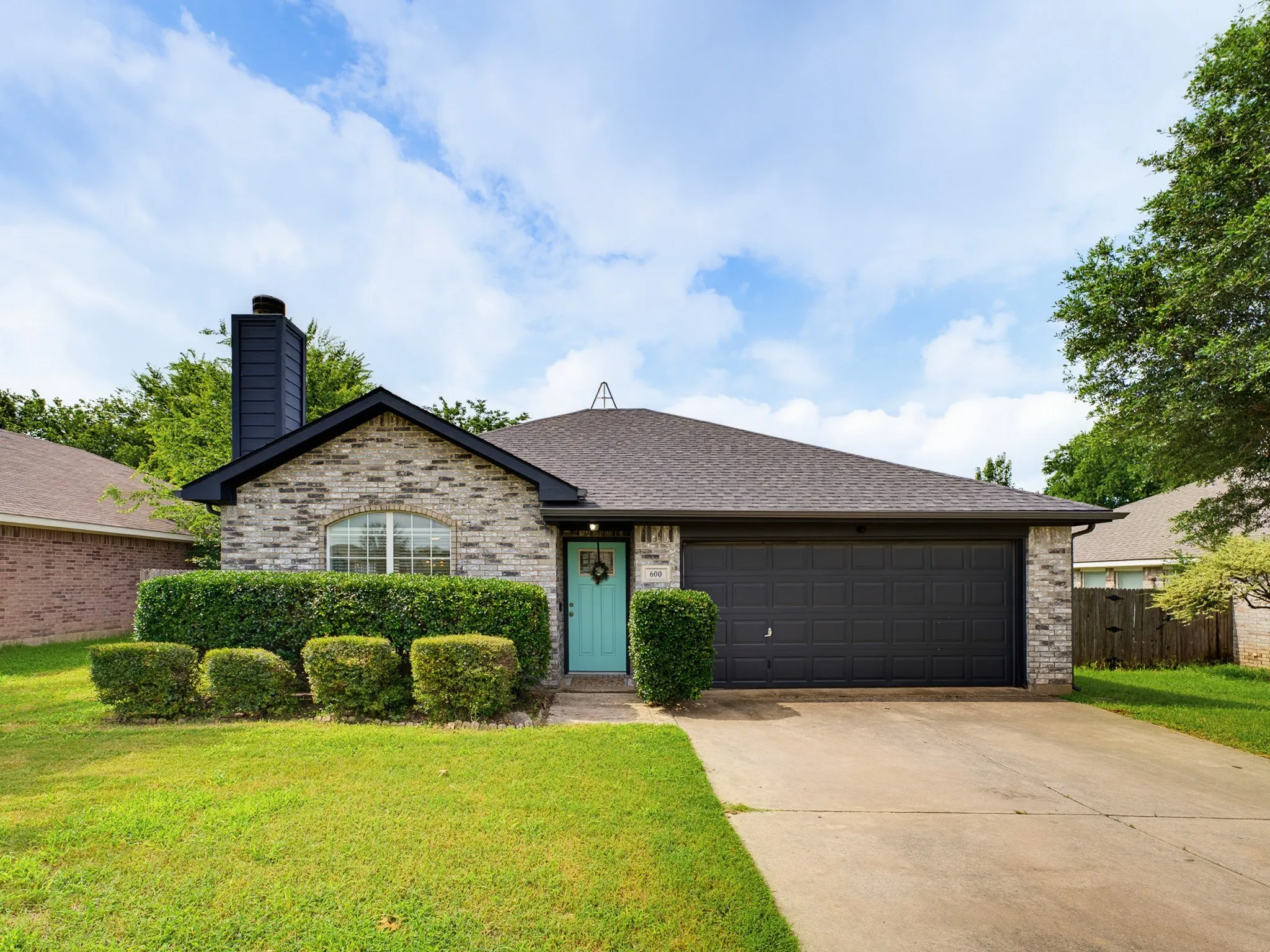 Brick facade with a contrasting turquoise entry door and a two-car garage