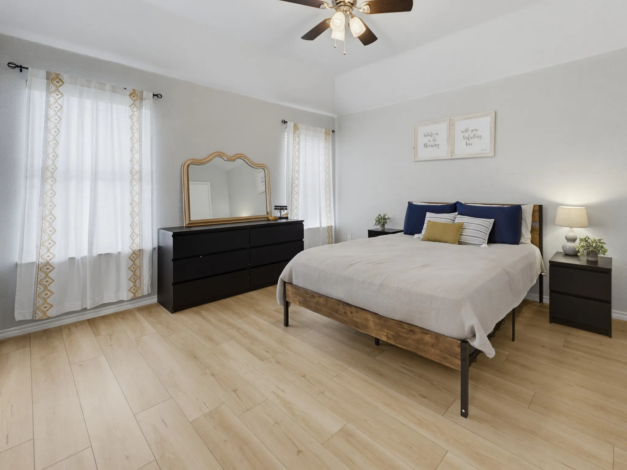 Spacious room featuring light wood-finish flooring, a tray ceiling, and a ceiling fan
