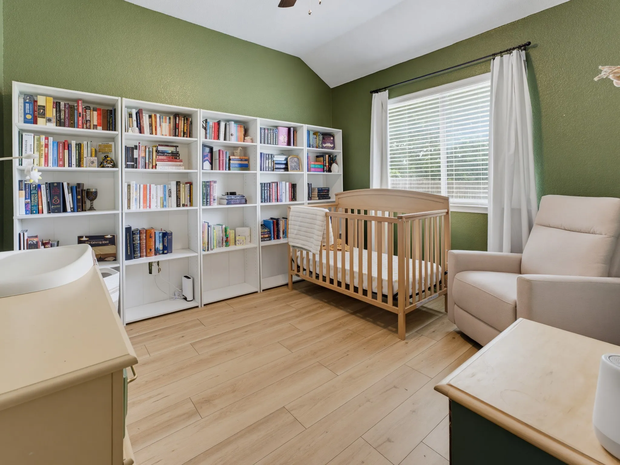 Vaulted ceiling room featuring light wood-finish flooring