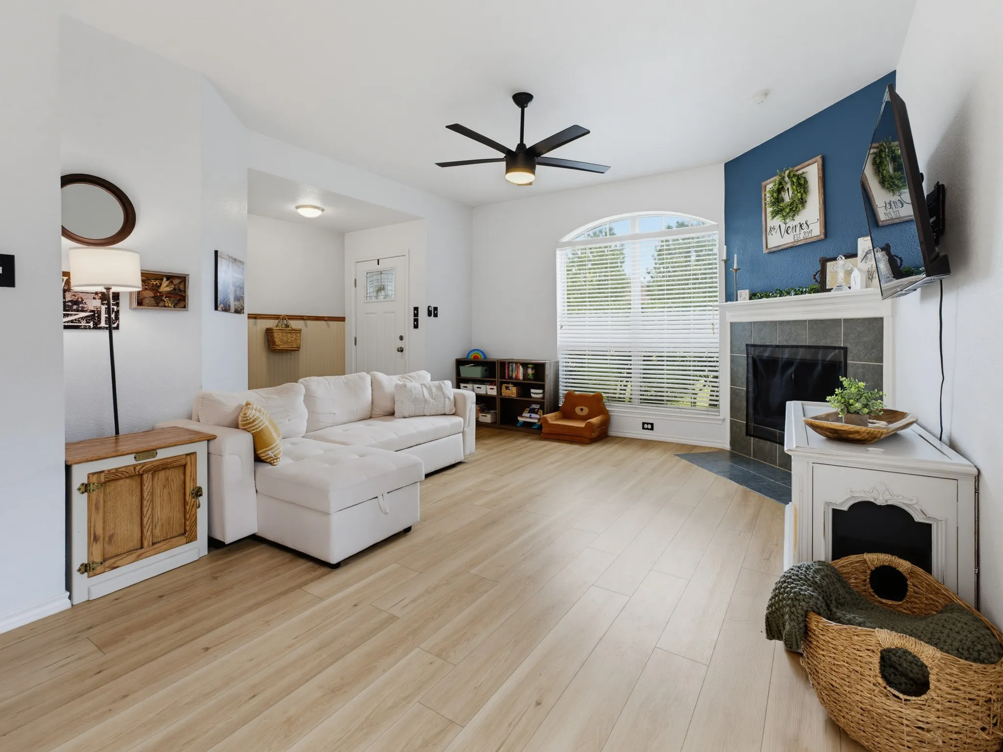 Spacious living area featuring light wood-finish flooring and a contemporary black ceiling fan