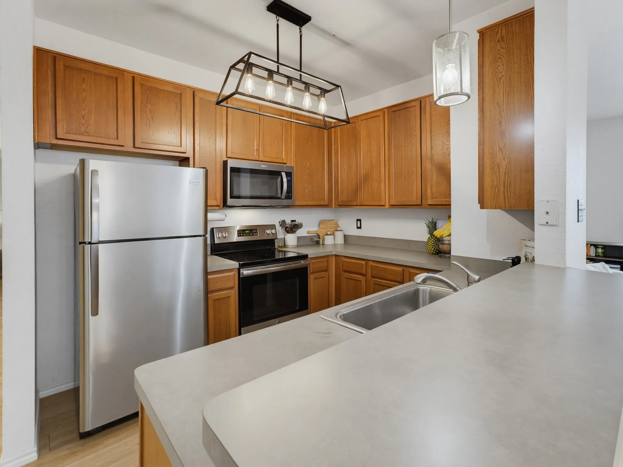 Kitchen featuring wood-finish cabinetry, stainless steel appliances, a double basin sink, and a gray countertop
