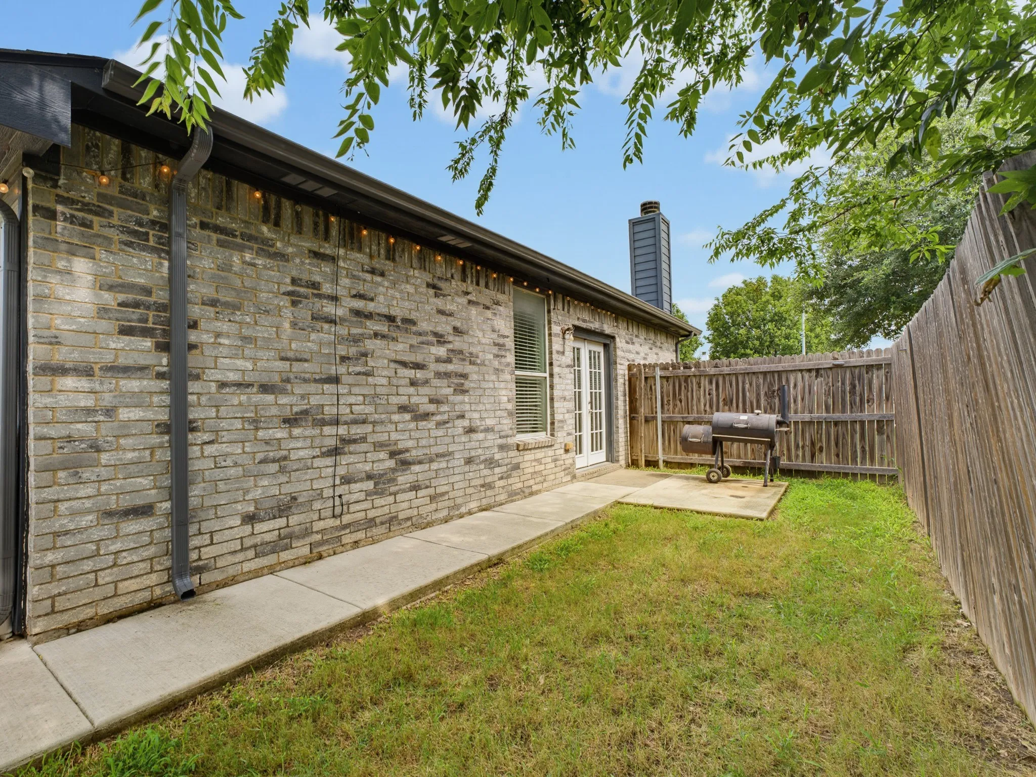 Private fenced backyard featuring a brick exterior and a concrete patio