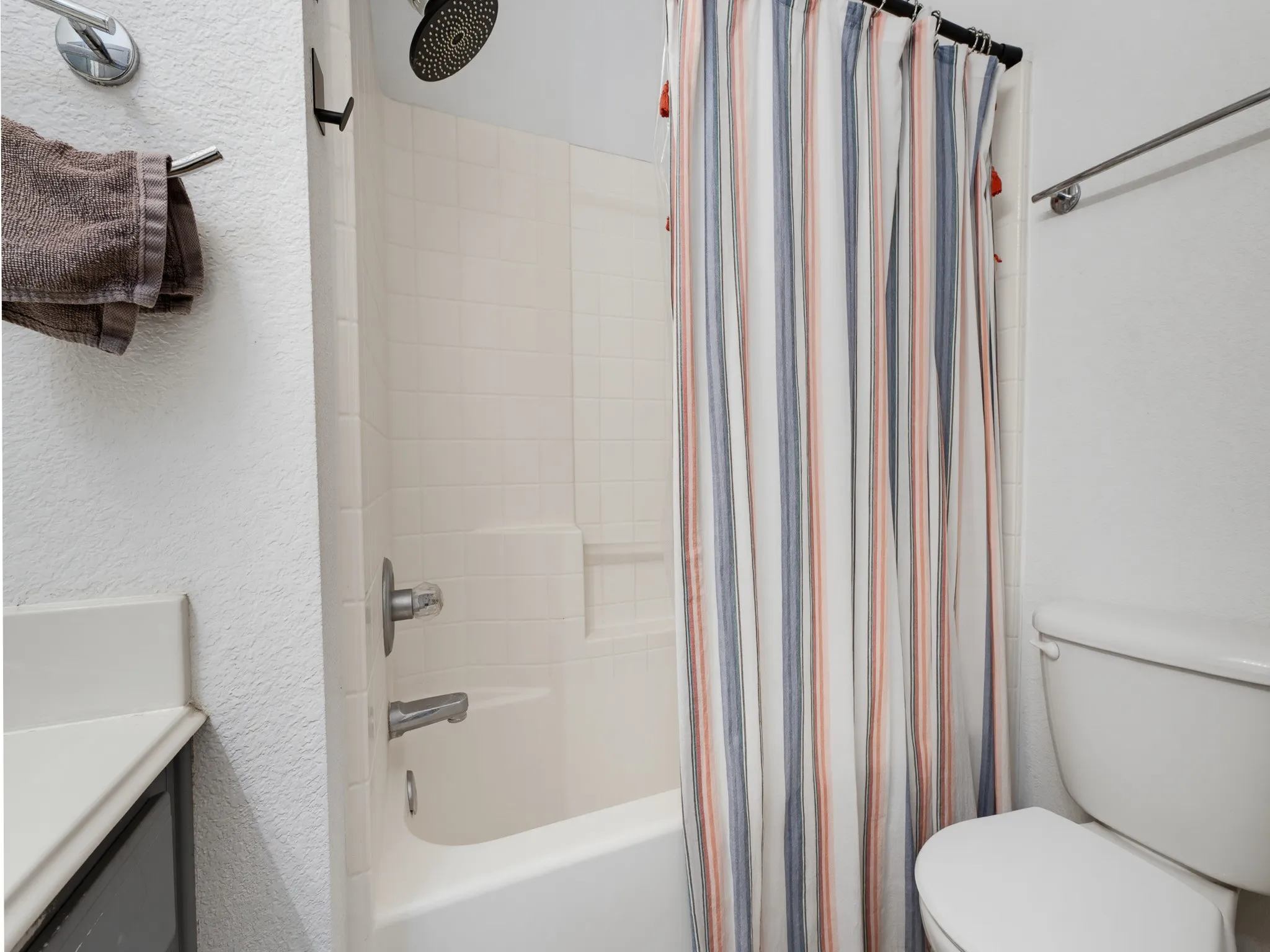 Tub and shower combination featuring a rainfall showerhead, white tiled surround, and integrated soap dish