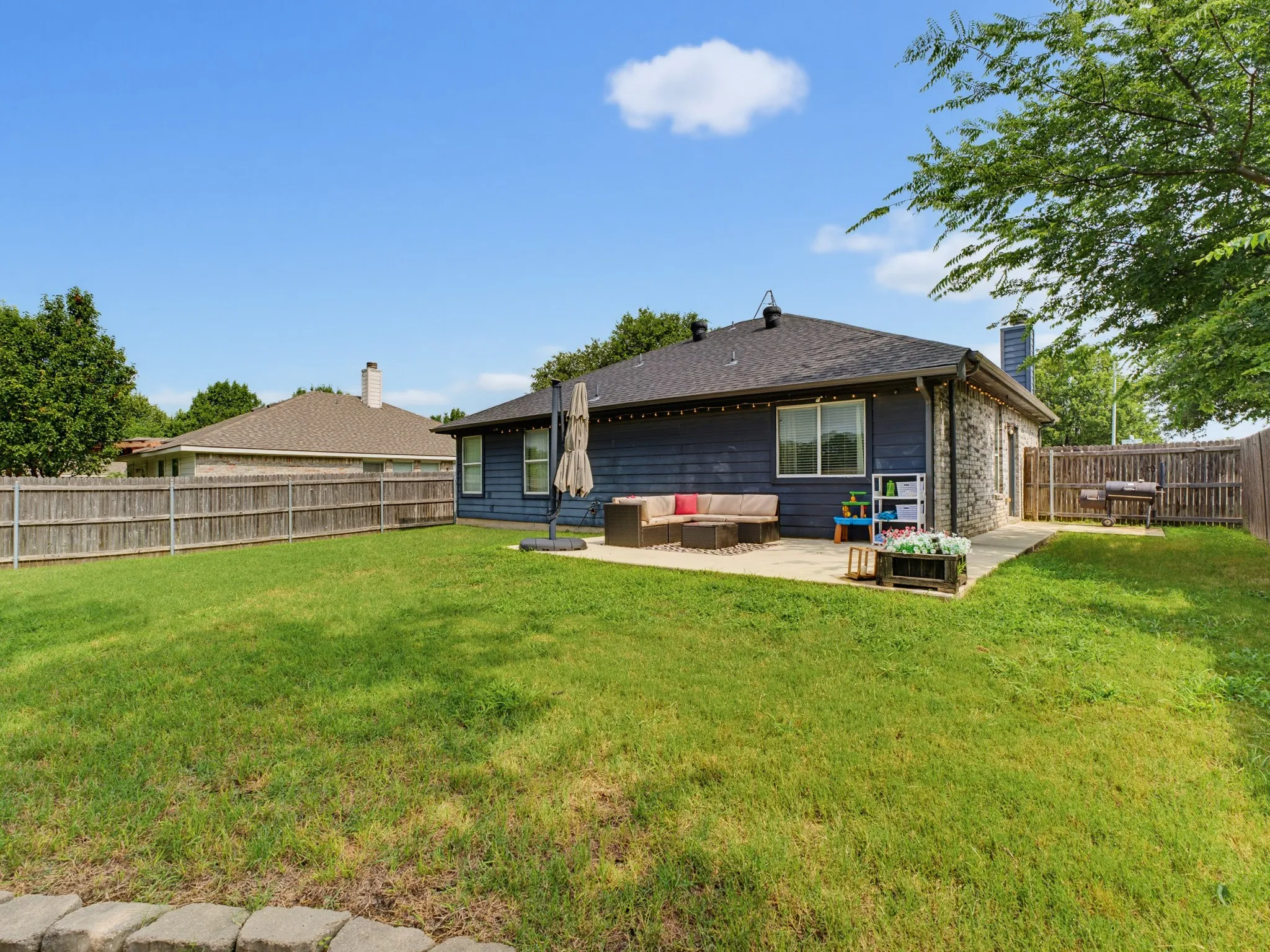 Spacious backyard featuring a large grass lawn, a concrete patio, and a privacy fence