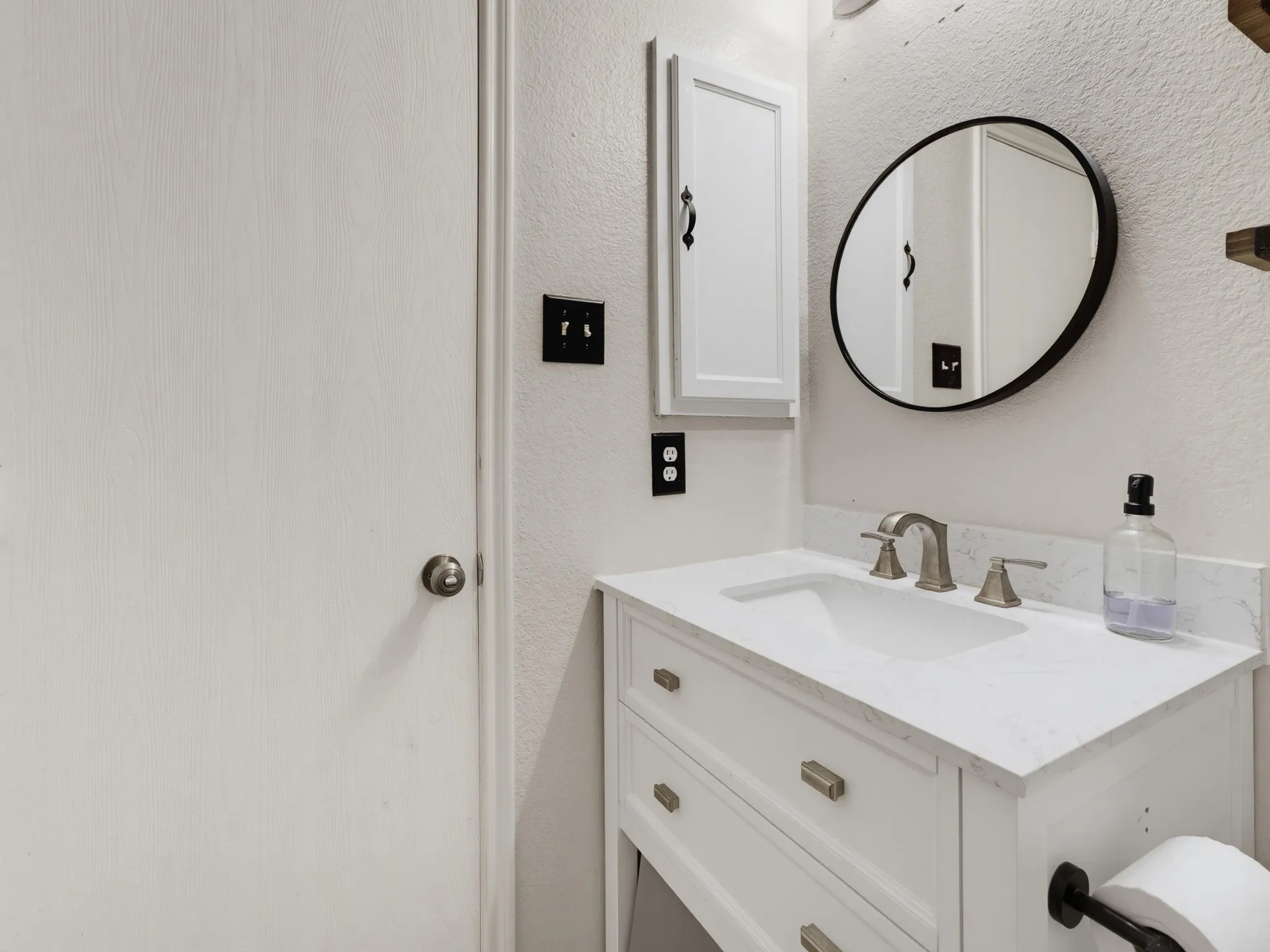 White vanity with a single basin sink and a stone-finish countertop