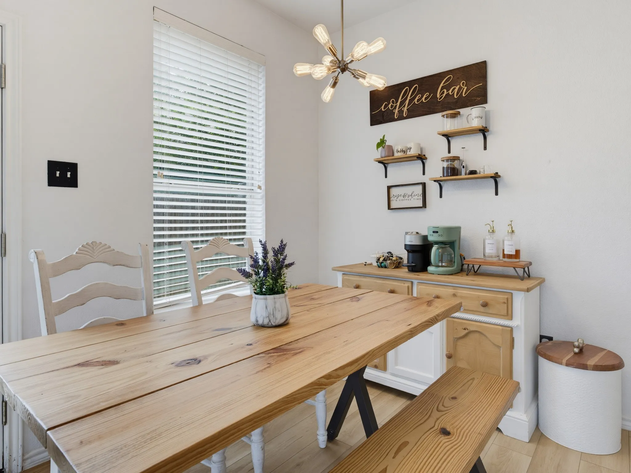Dining area featuring light wood-finish flooring, a contemporary sputnik-style ceiling light fixture, and a window with horizontal blinds