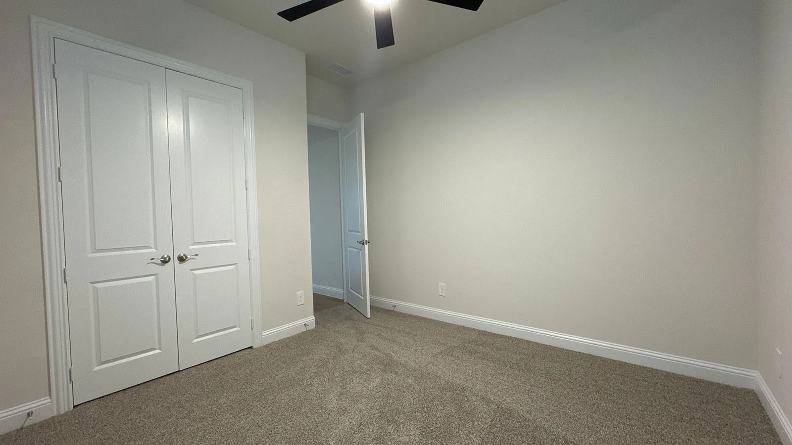 Wall-to-wall carpeting, ceiling fan with light fixture, and double-panel closet doors