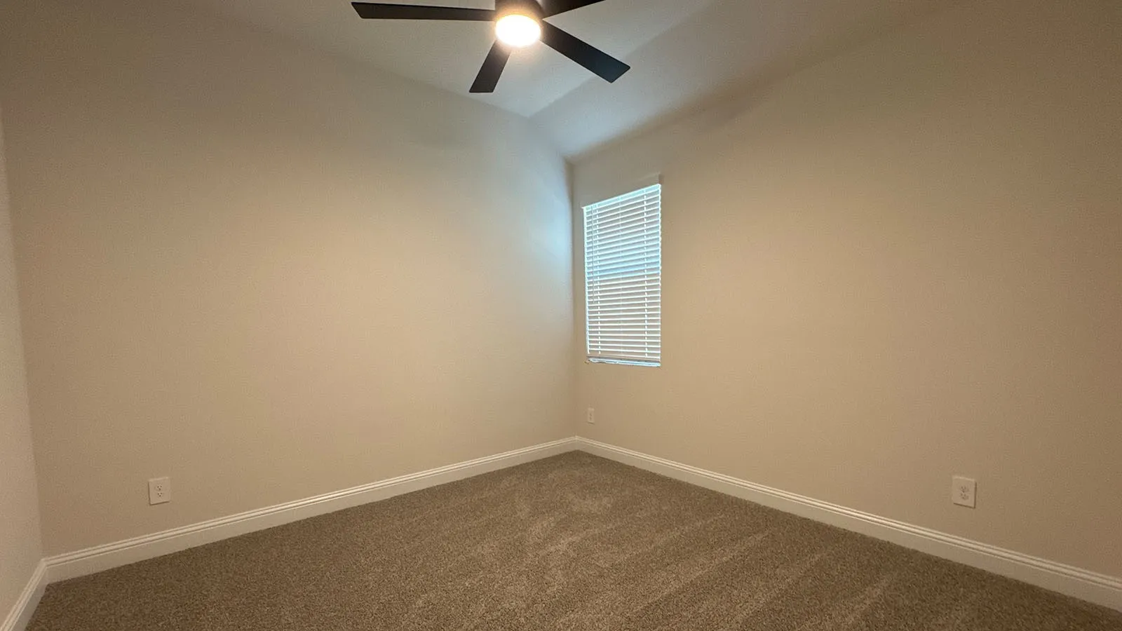 Vaulted ceiling, ceiling fan with integrated lighting, window with blinds, light-colored walls, and neutral carpeting