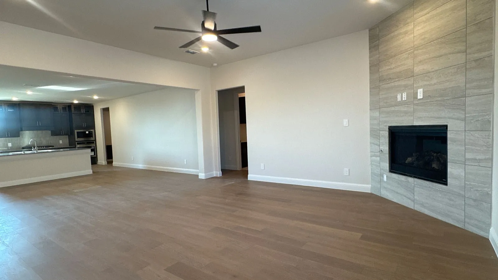 Wood-finish flooring, ceiling fan with integrated lighting, tiled fireplace surround, built-in fireplace, and recessed lighting