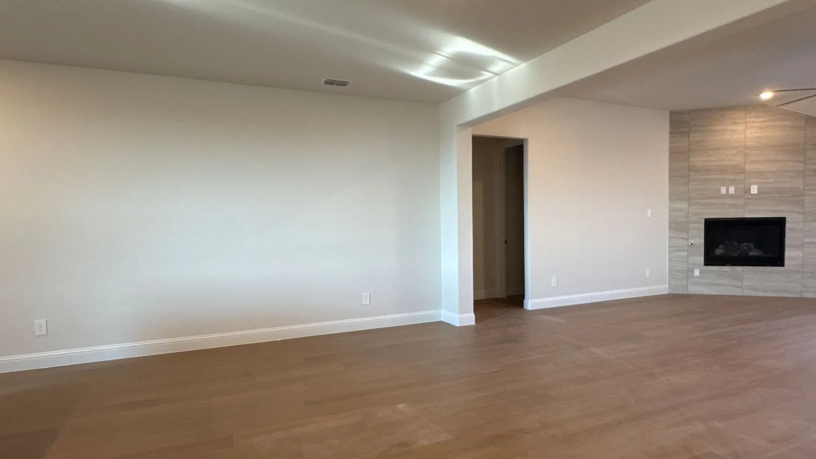Wood-finish flooring, recessed lighting, and a modern fireplace with a tile surround