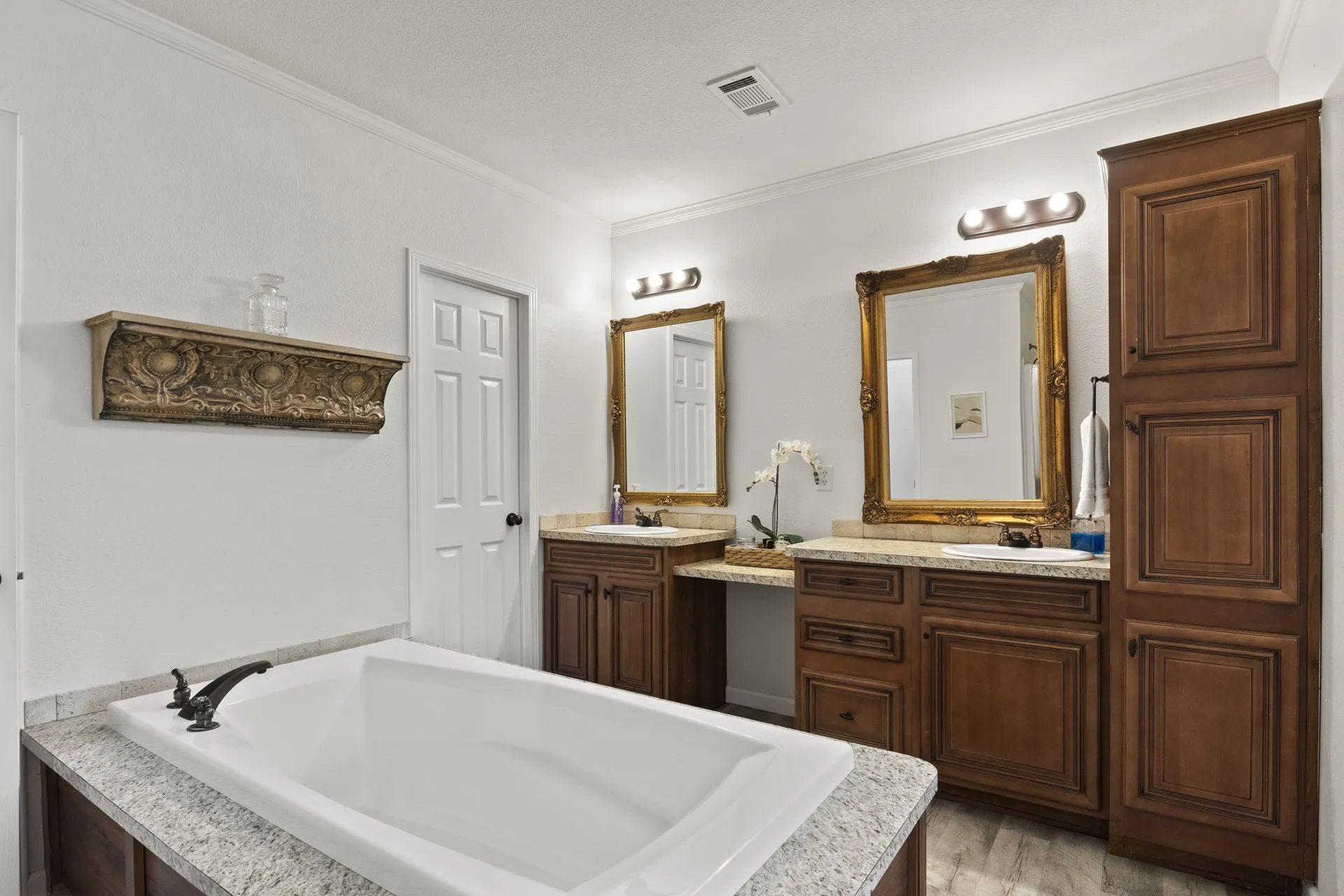 Bathroom featuring hardwood / wood-style floors, a bath to relax in, ornamental molding, and dual vanity