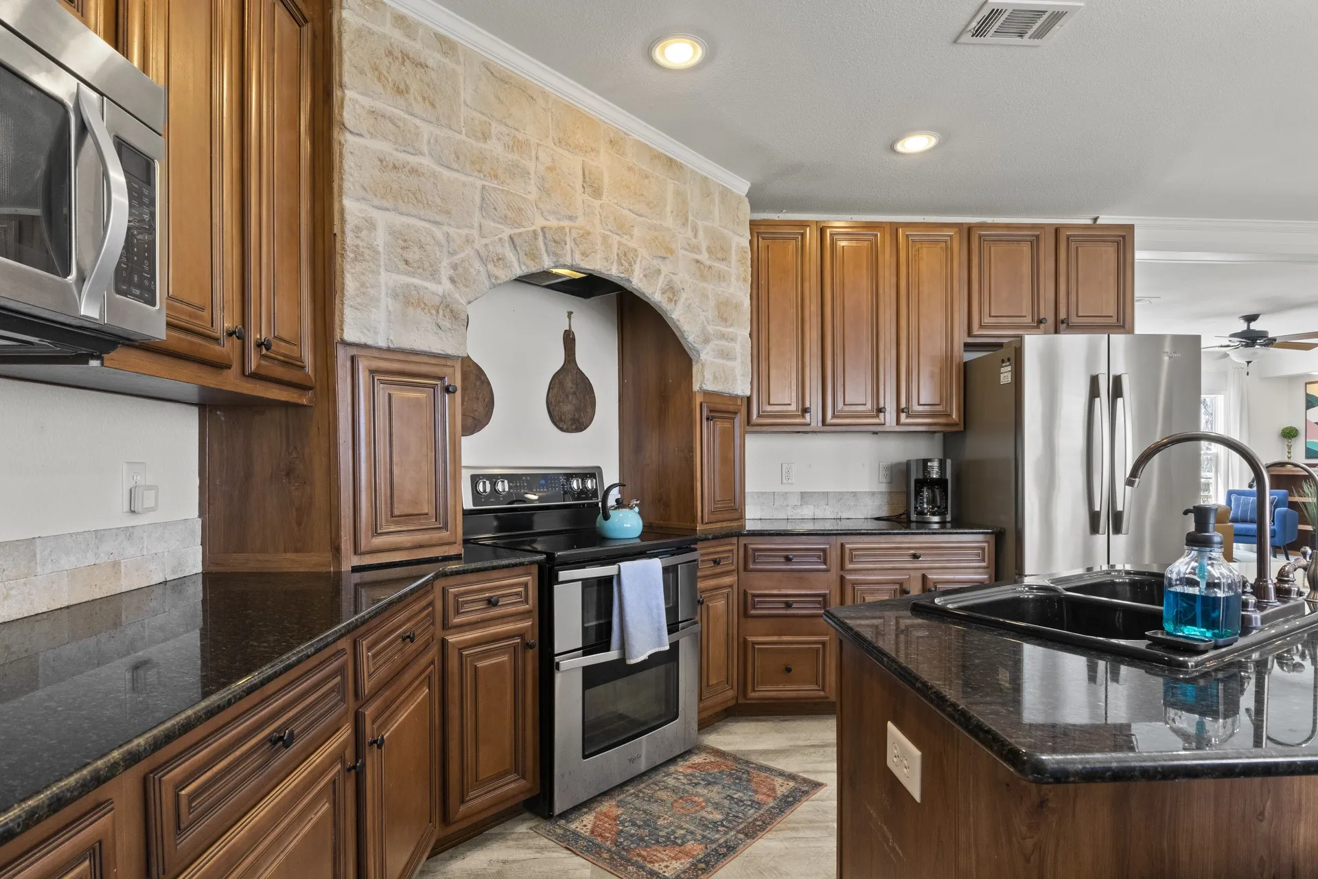 Kitchen with dark stone countertops, ceiling fan, stainless steel appliances, and ornamental molding