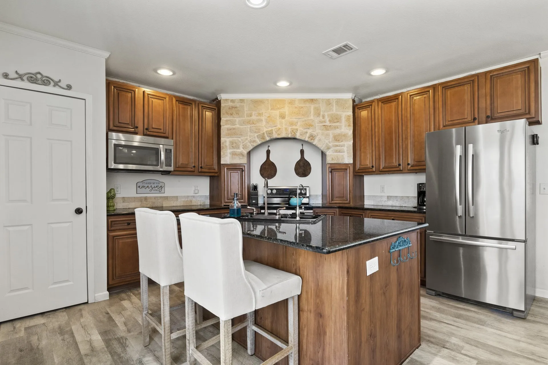 Kitchen featuring a center island, light wood-type flooring, ornamental molding, appliances with stainless steel finishes, and sink