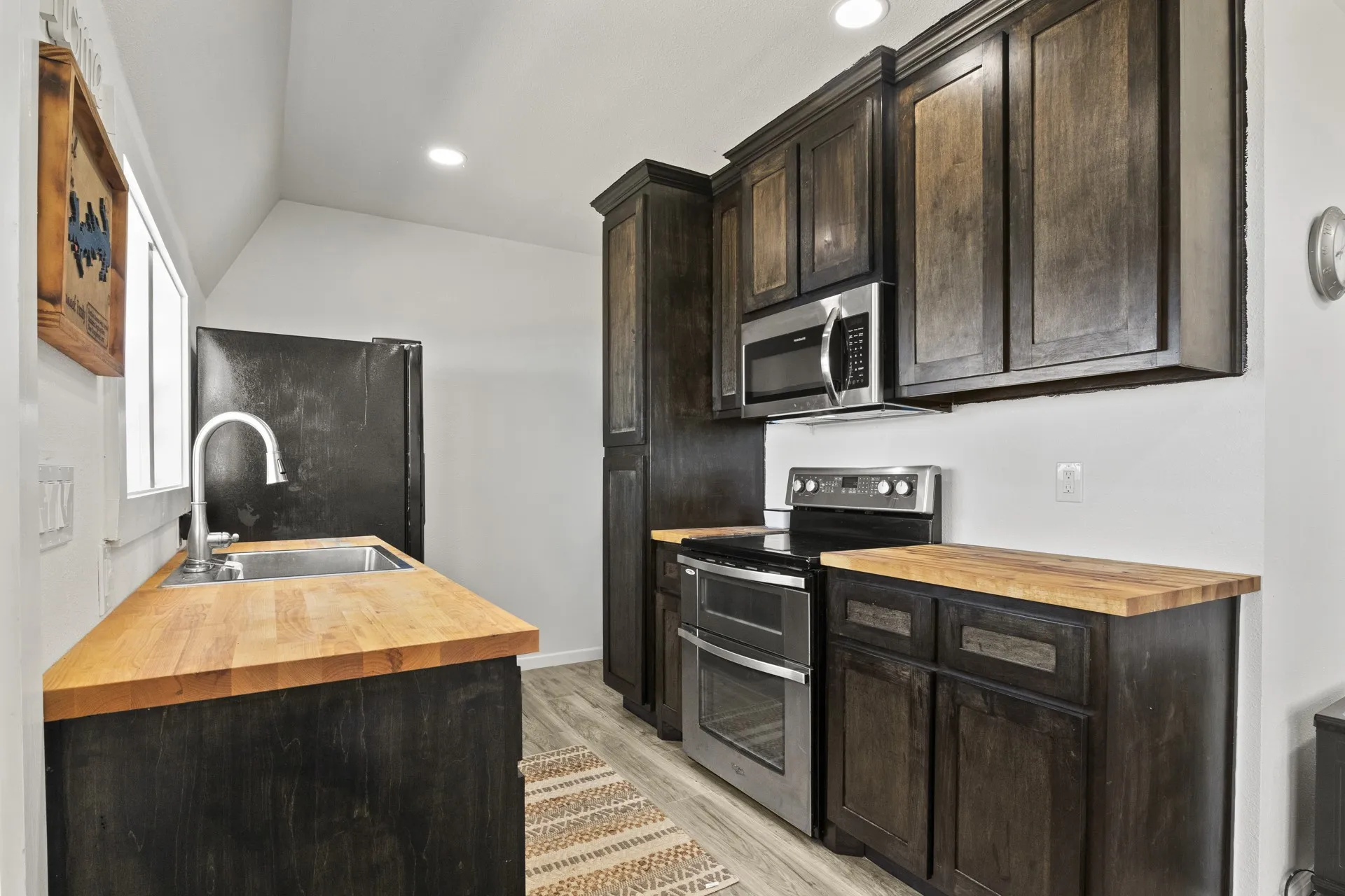 Kitchen featuring appliances with stainless steel finishes, wood counters, light hardwood / wood-style floors, and sink