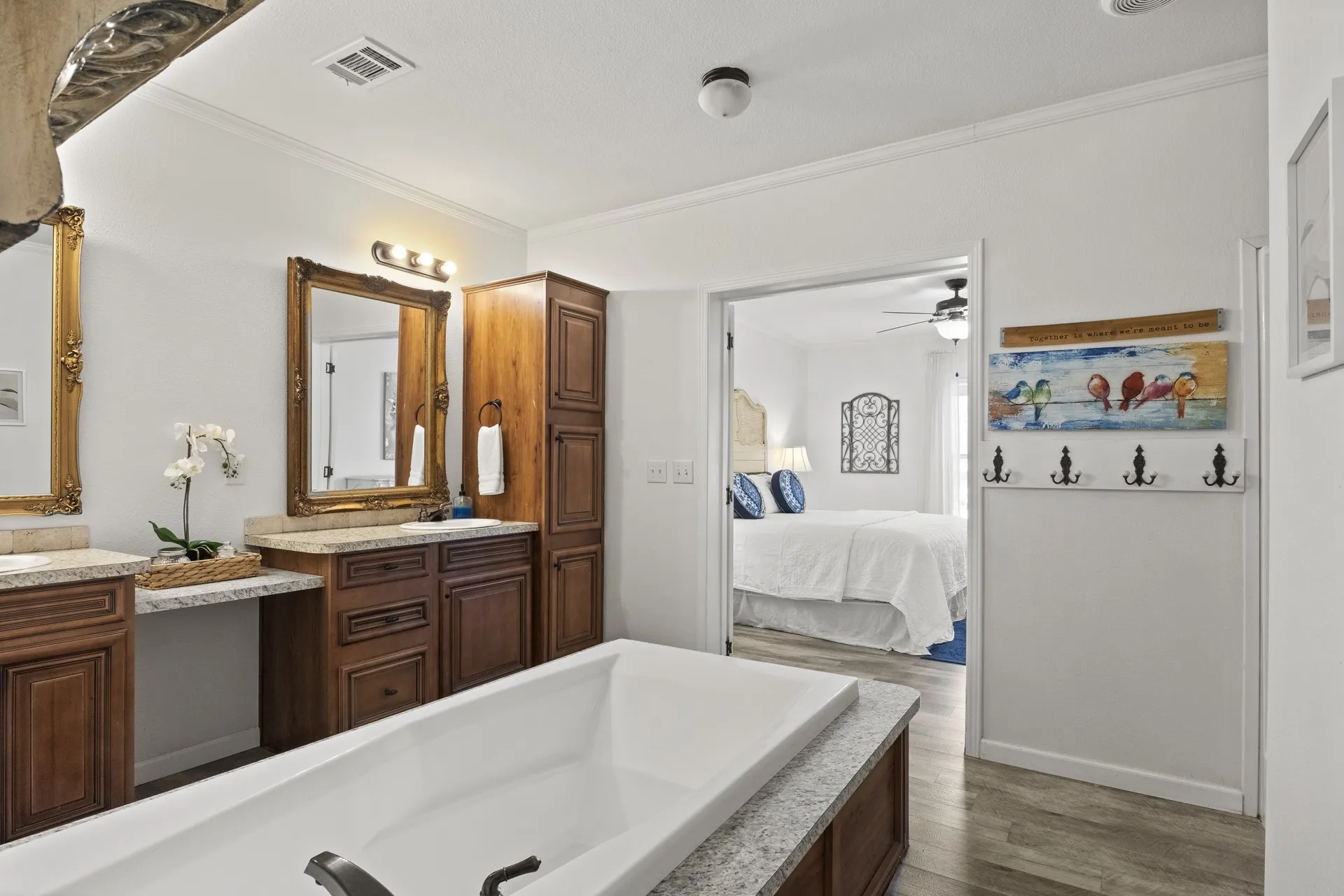 Bathroom with ceiling fan, hardwood / wood-style flooring, vanity with extensive cabinet space, and ornamental molding