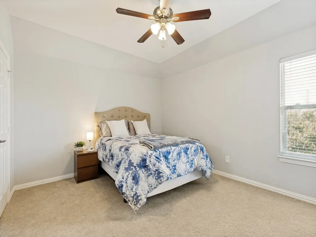 Carpeted room featuring a ceiling fan with integrated lighting, a window with blinds, and white baseboards