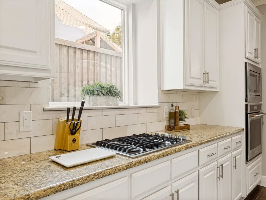 Kitchen featuring a gas cooktop, granite countertops, white cabinetry with contemporary hardware, and a subway tile backsplash