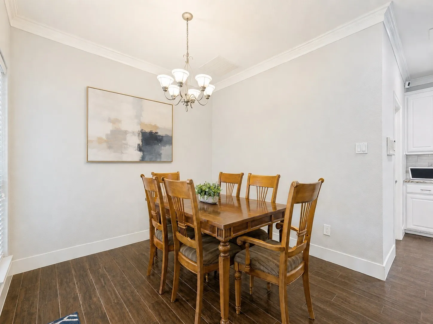 Dining space featuring dark wood-finish flooring, white baseboards, and crown molding