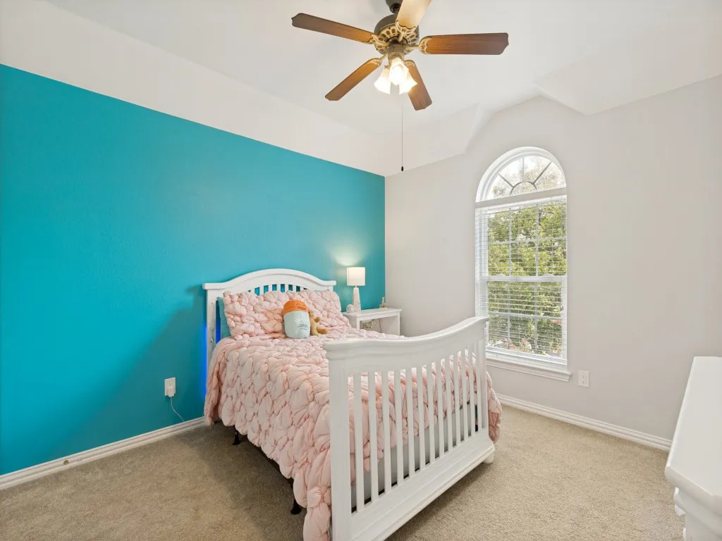 Room featuring a prominent arched window, vaulted ceiling, and ceiling fan with light fixture