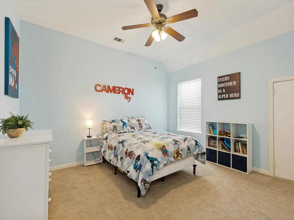 Carpeted bedroom featuring vaulted ceilings, a ceiling fan with light fixture, and windows with blinds
