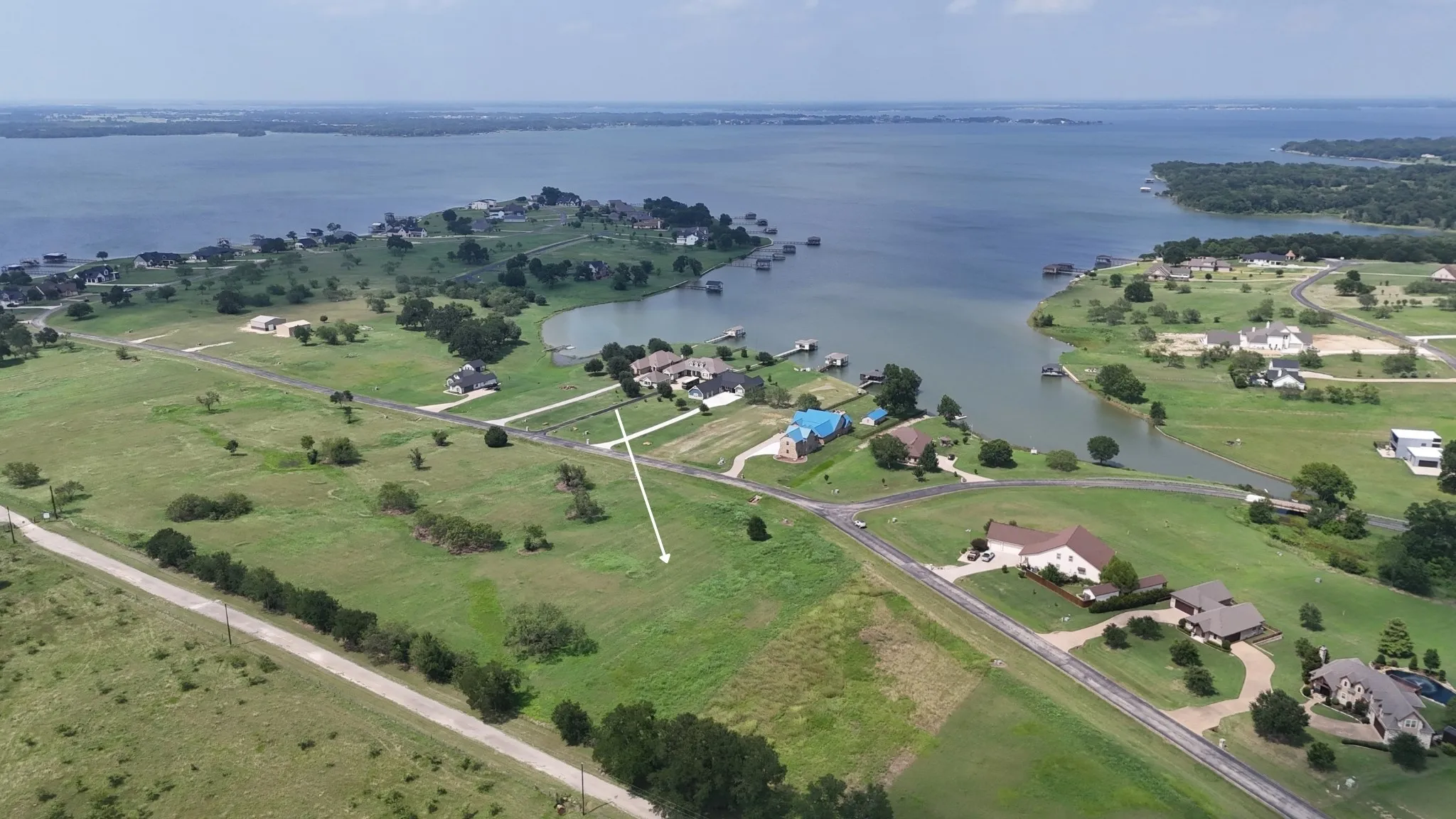 Wide aerial view illustrating neighboring custom homes and open surroundings.