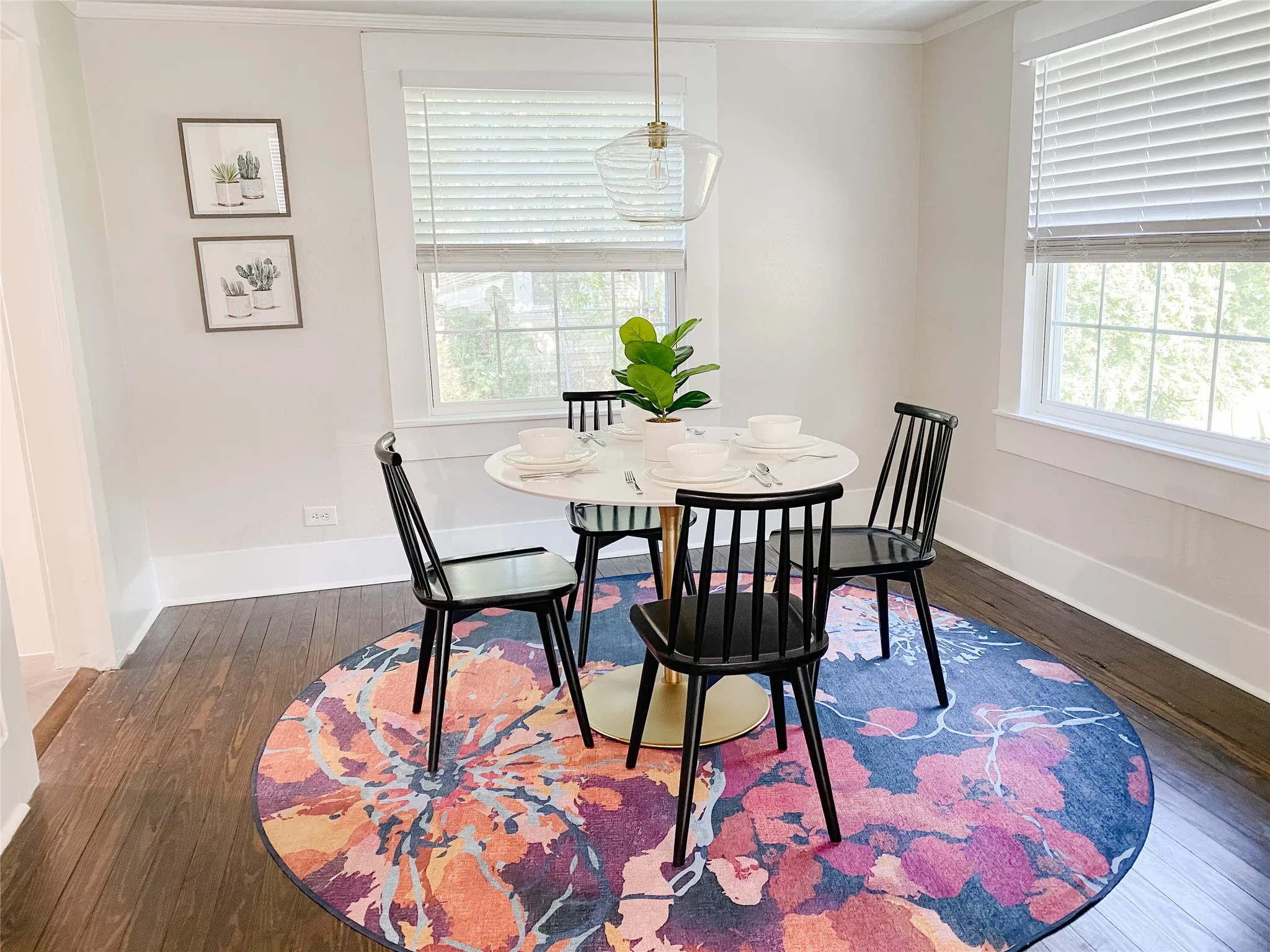 Dining area featuring warm wood-finish flooring and two bright windows with blinds
