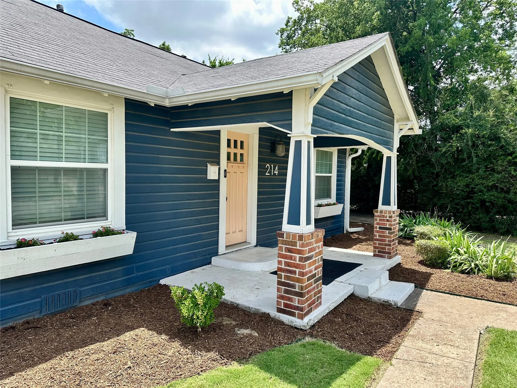 Charming exterior featuring blue siding, white trim, and a covered front porch with brick-clad columns