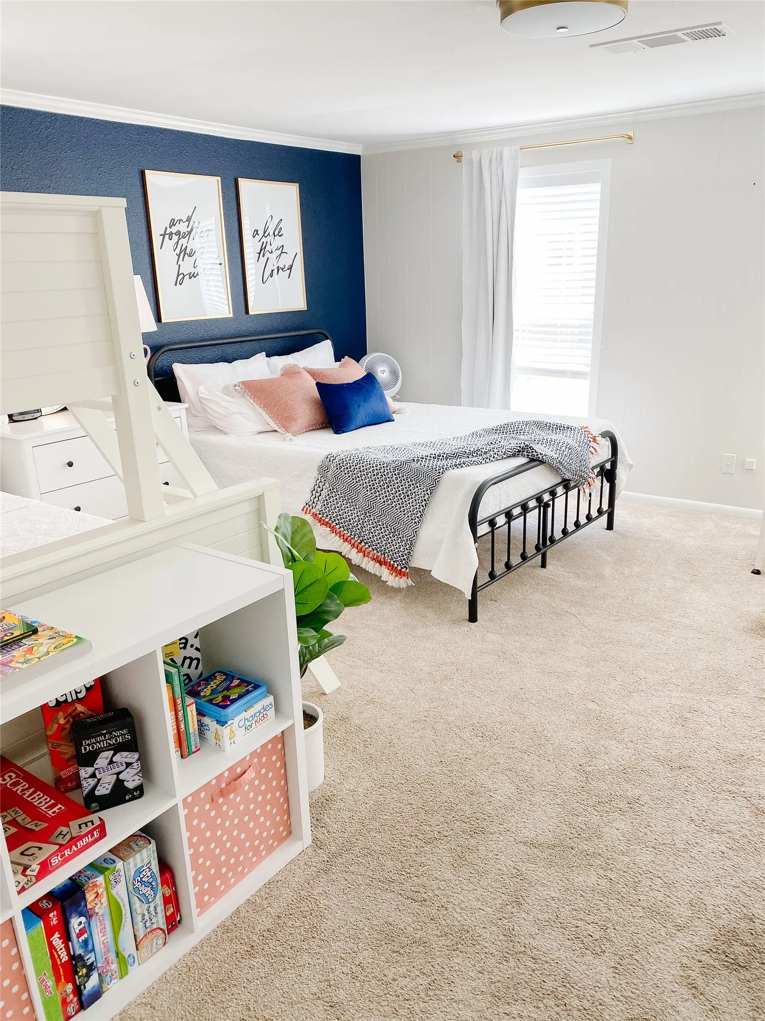 Carpeted bedroom featuring a deep blue accent wall, crown molding, and a white window blind