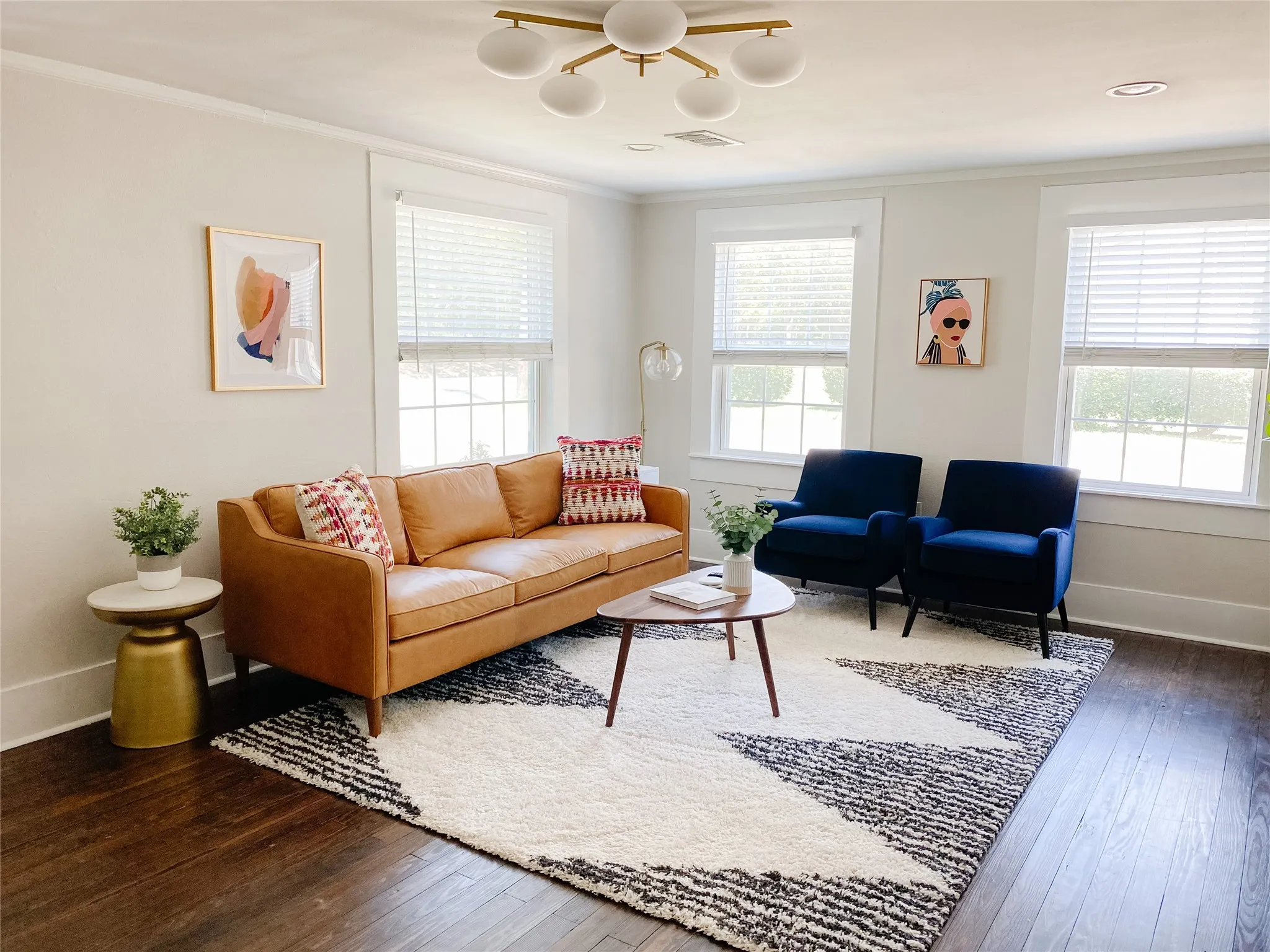 Spacious room featuring dark wood-finish flooring, multiple windows with blinds, a modern ceiling light fixture, crown molding, and recessed lighting