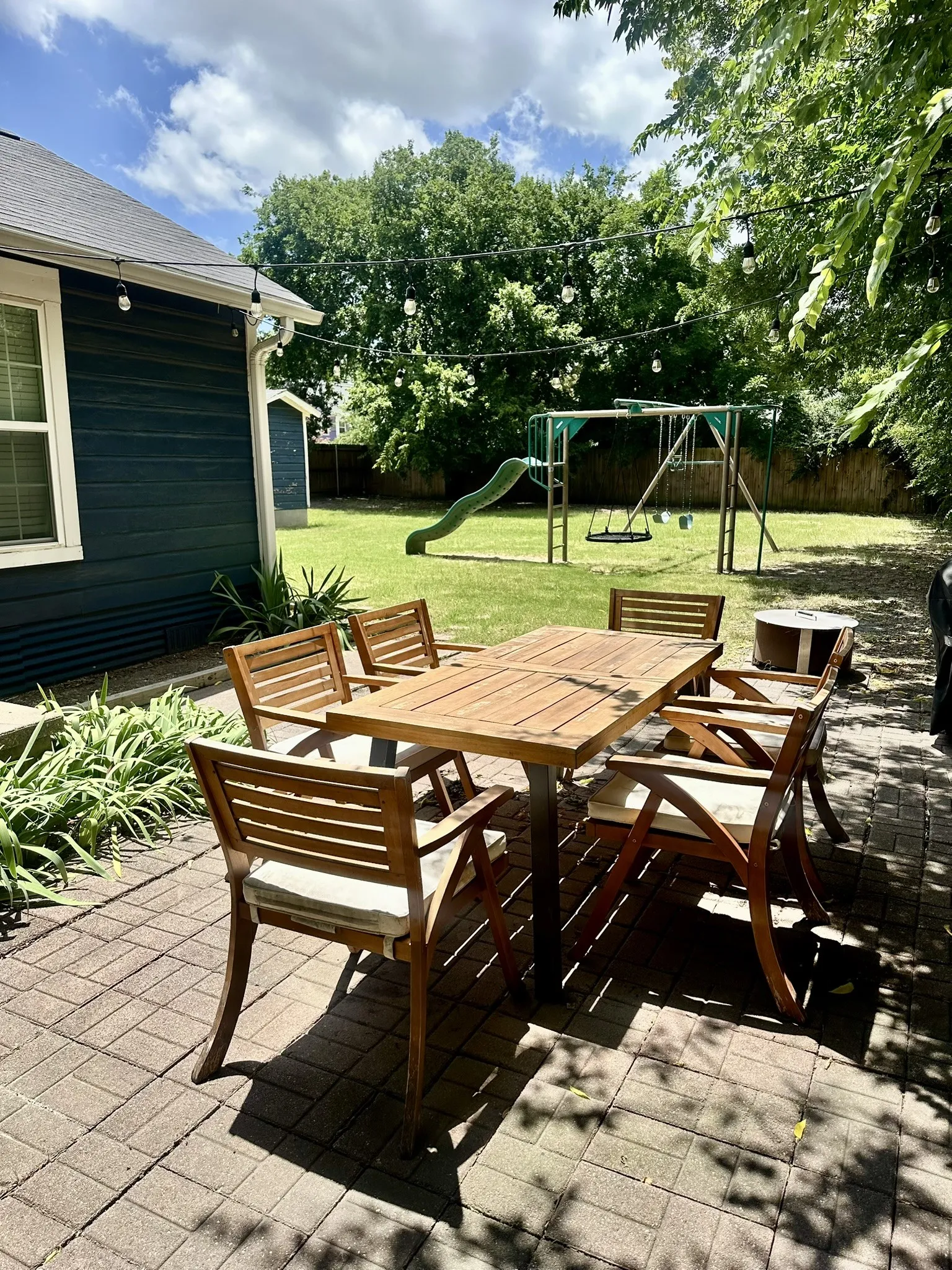 Expansive backyard featuring a brick paver patio, a manicured lawn, and mature trees