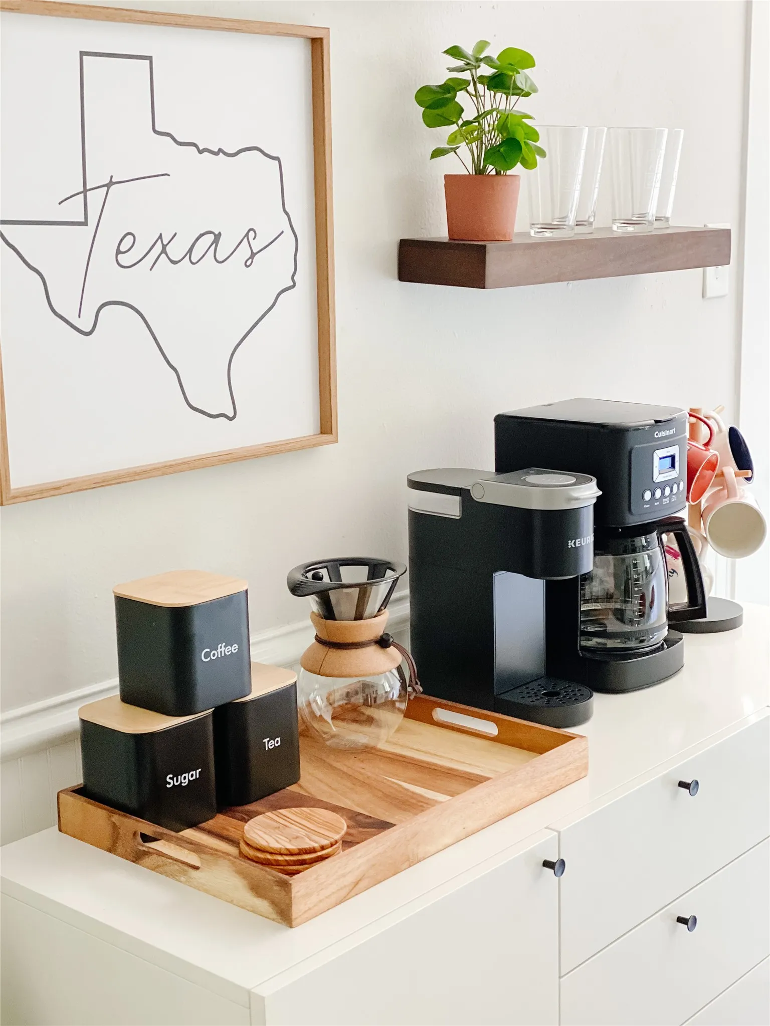White cabinetry with black drawer pulls, featuring an integrated floating wood shelf
