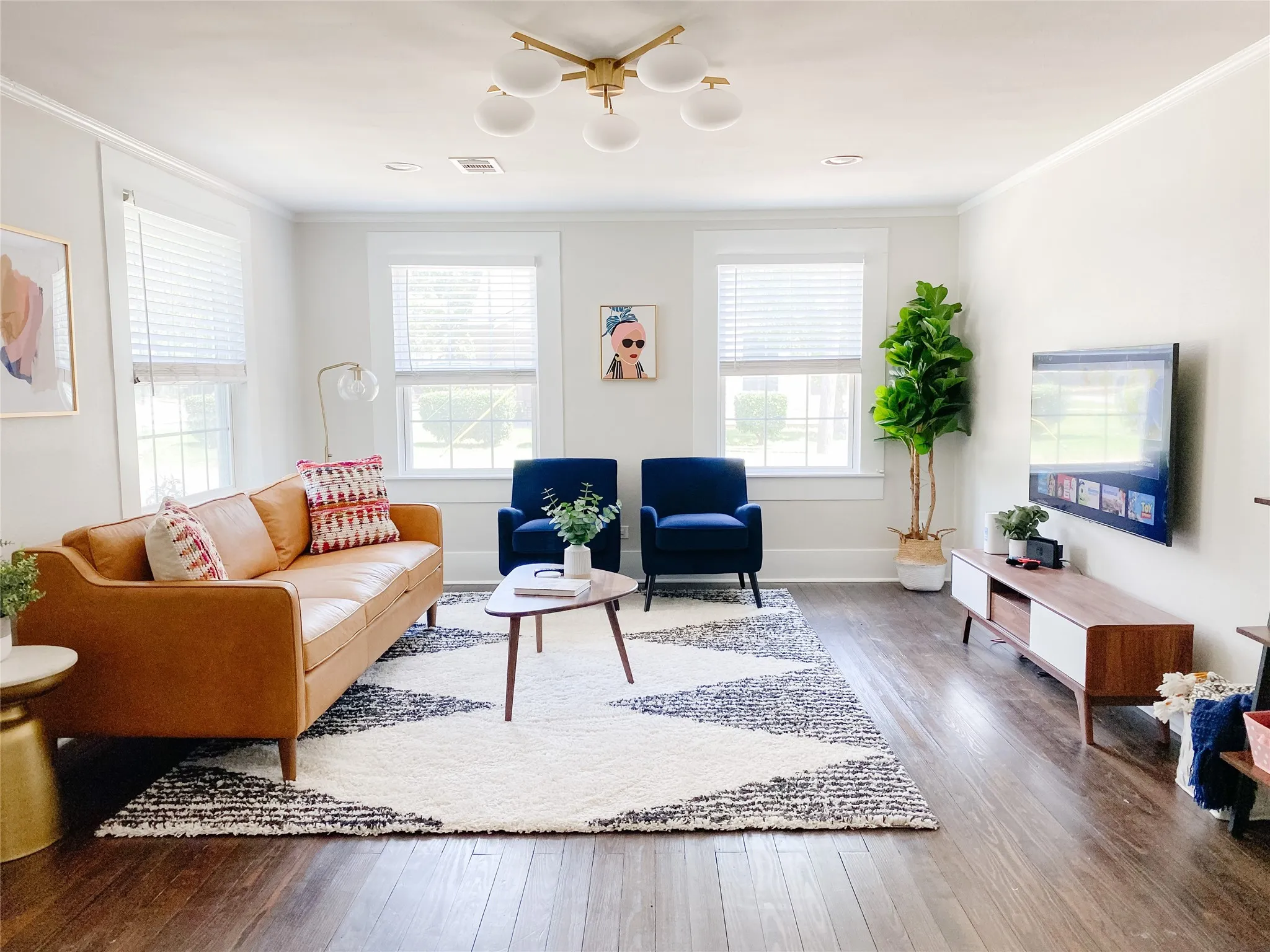 Spacious living area featuring dark wood-finish flooring, white walls, and a contemporary ceiling light fixture