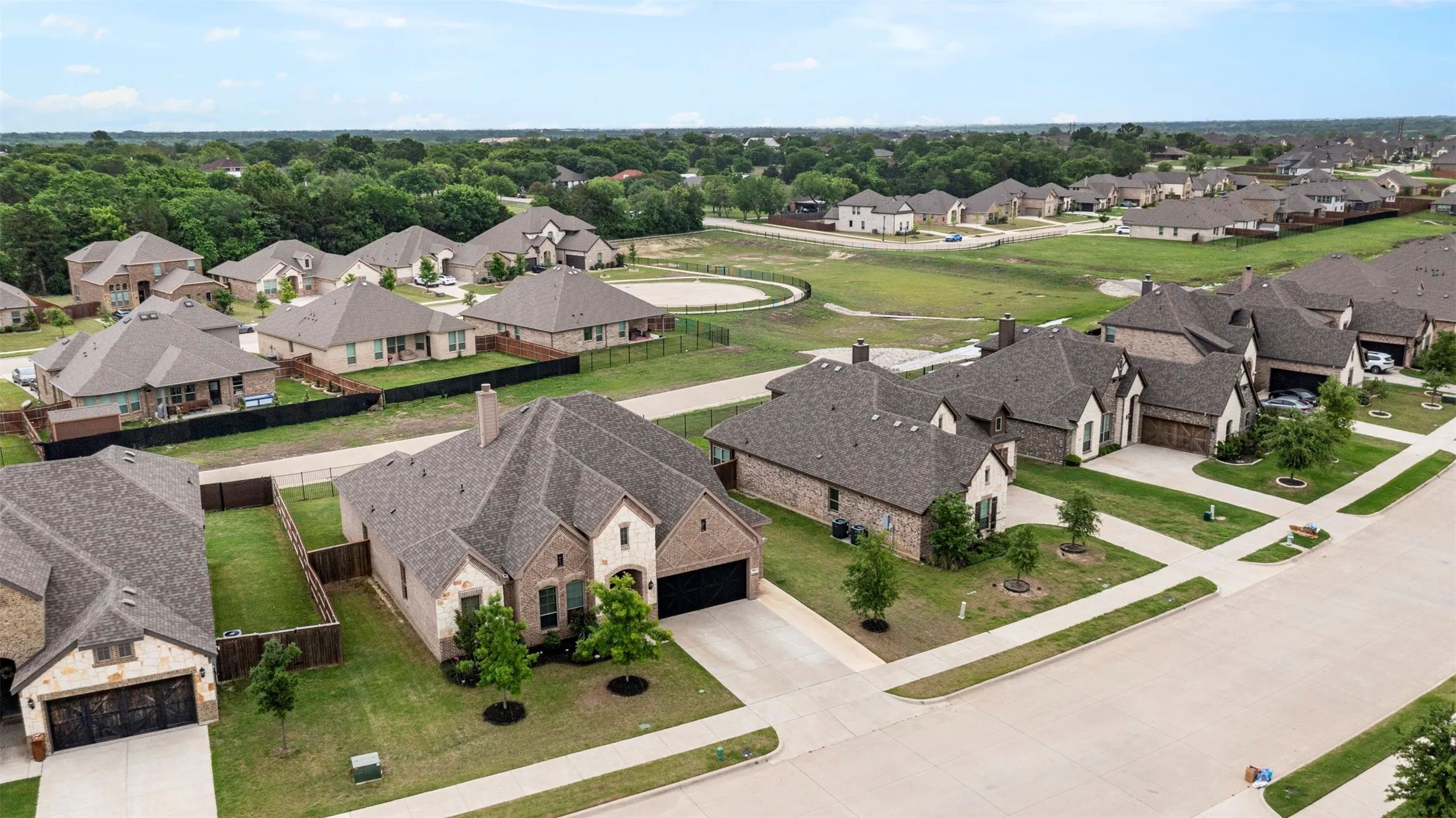 Expansive residential neighborhood featuring single-family homes with brick and stone exteriors, asphalt shingle roofs, and attached garages