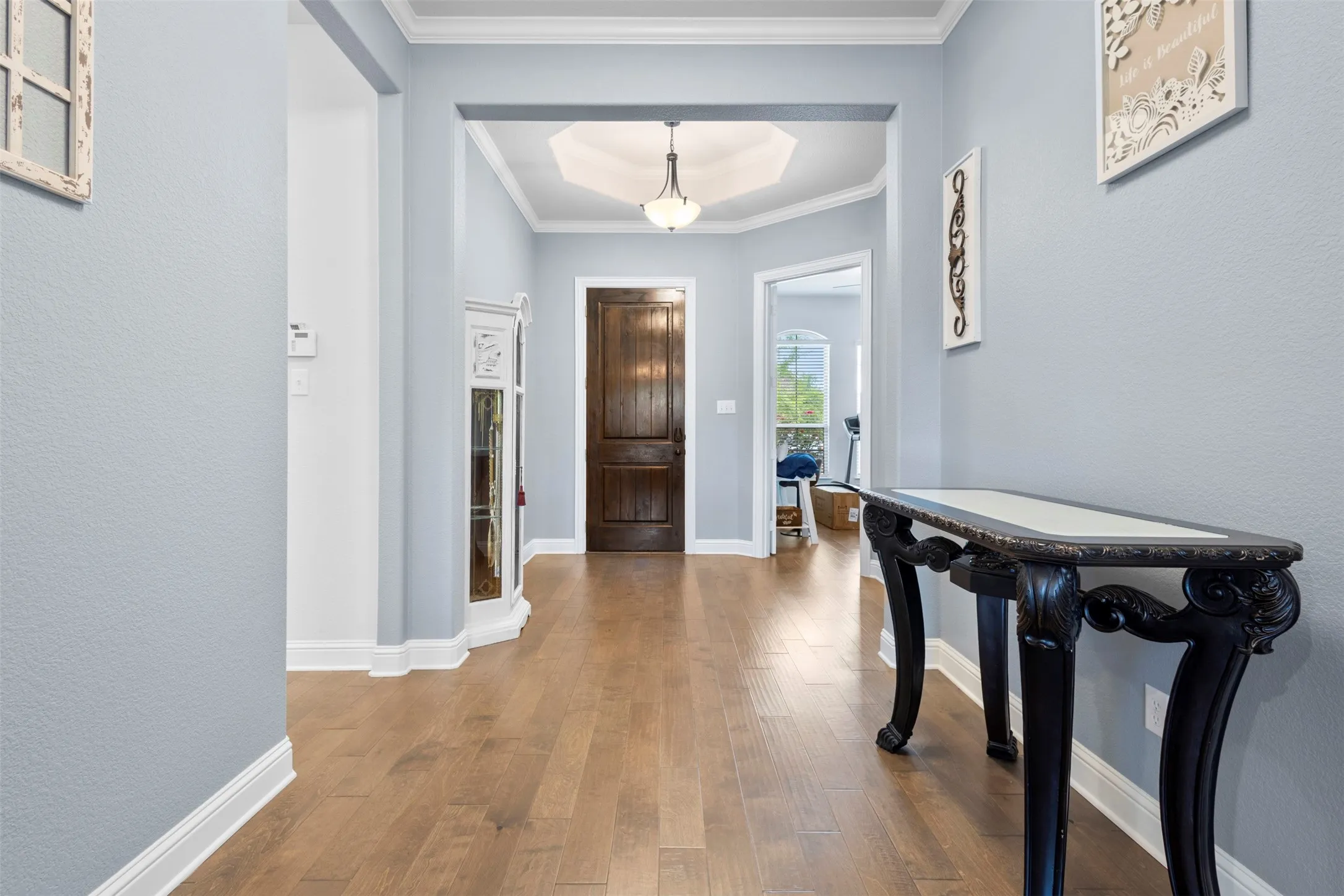 Entryway featuring wood-finish flooring, light blue wall paint, and white crown molding