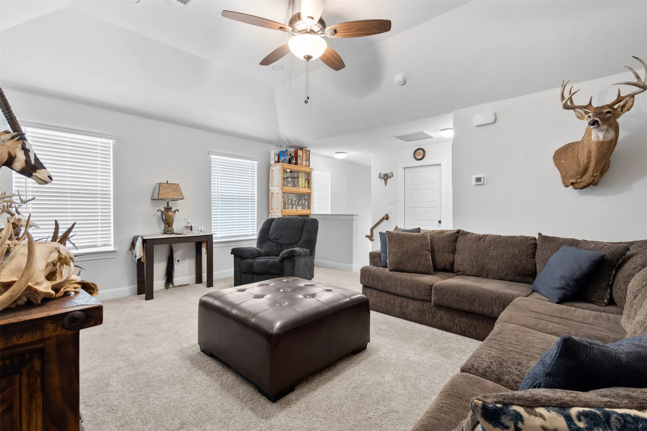 Carpeted secondary living space featuring a vaulted ceiling with a ceiling fan