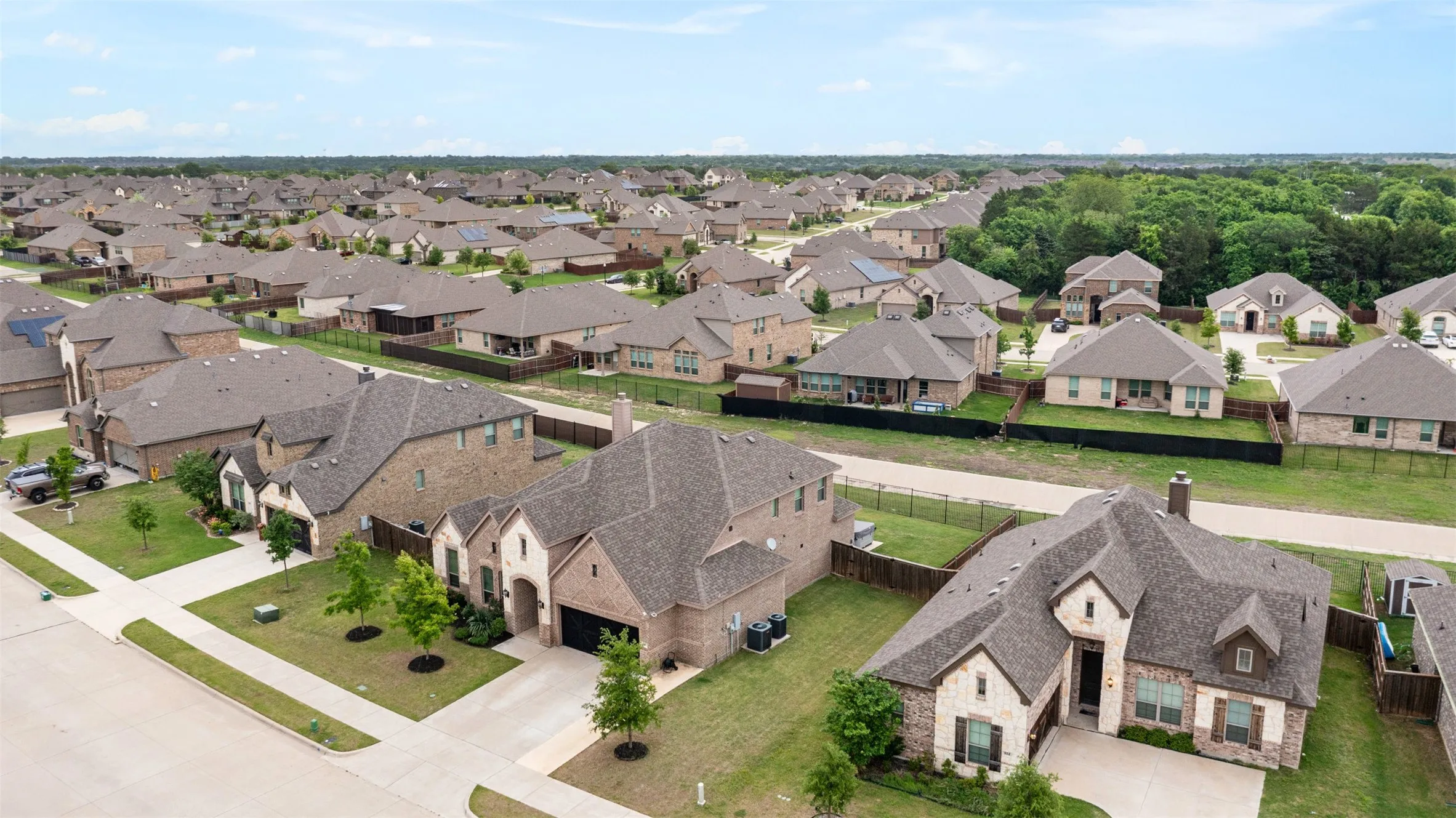 Expansive residential development featuring a variety of single-family homes, mature landscaping, and uniform fencing